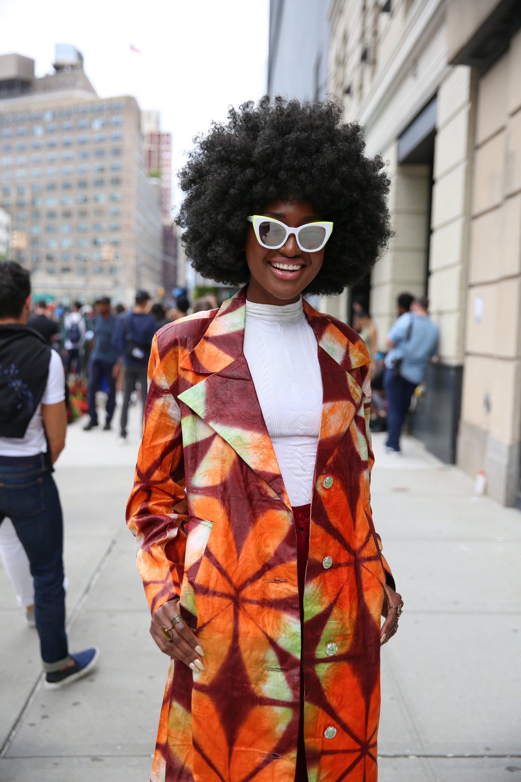 Flower power takes the lead in this retro fashion week look. Splashes of orange, green and burgundy are offset by this guest's white polo neck top and matching shades.