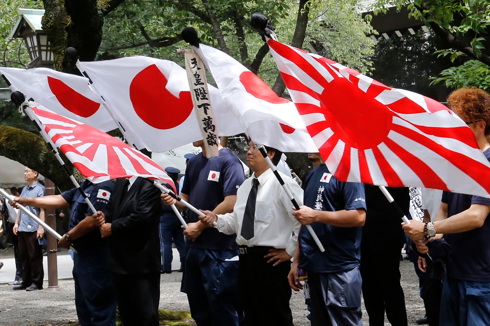 Members of a right-wing group holding the 'rising sun' flag (right) and Japan's national flag at Yasukuni Shrine in Tokyo in August