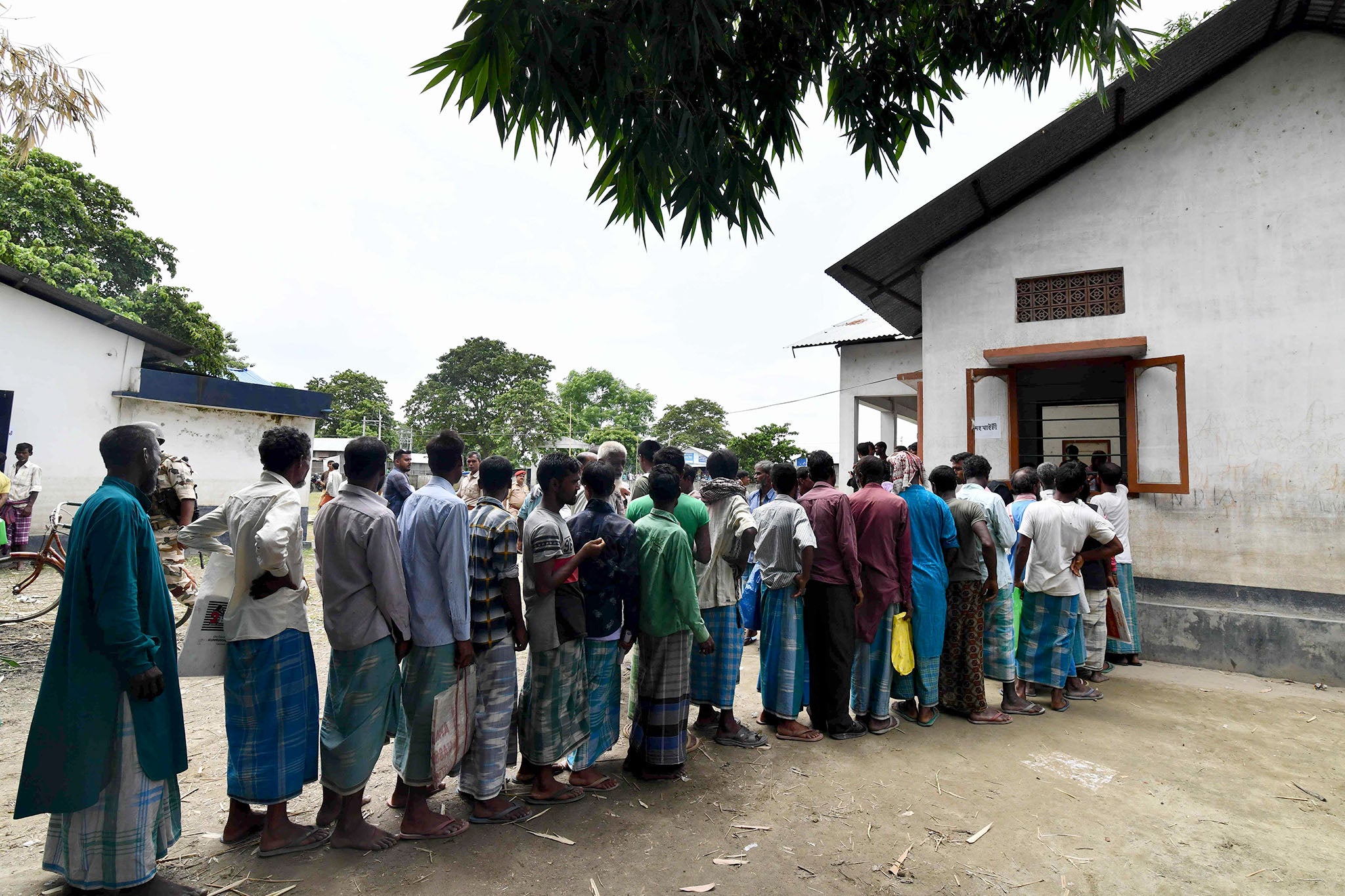 People queue to check their status at an office in the village of Pavakati