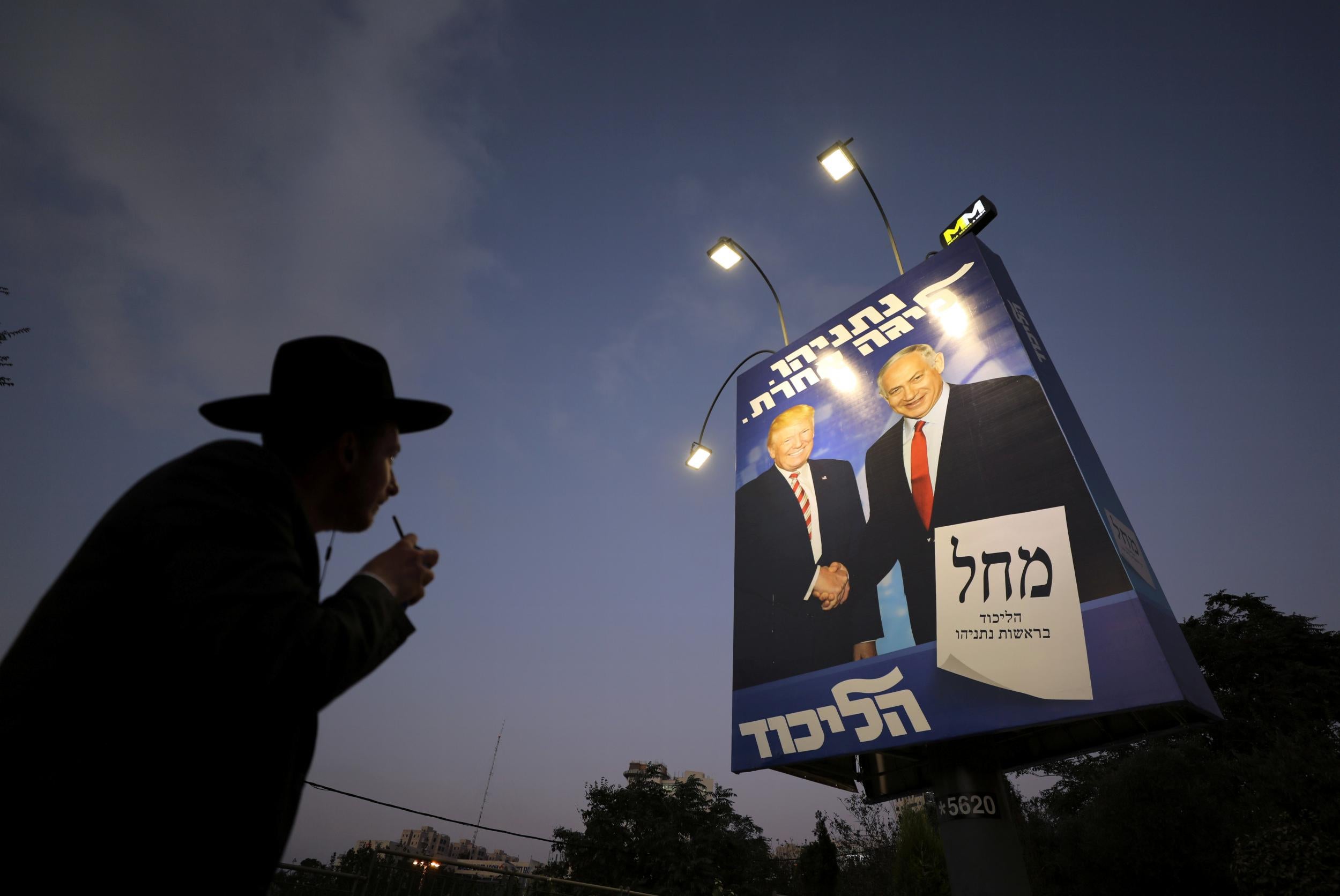 An ultra-Orthodox Jewish man walks past a Likud party election campaign banner (Reuters)