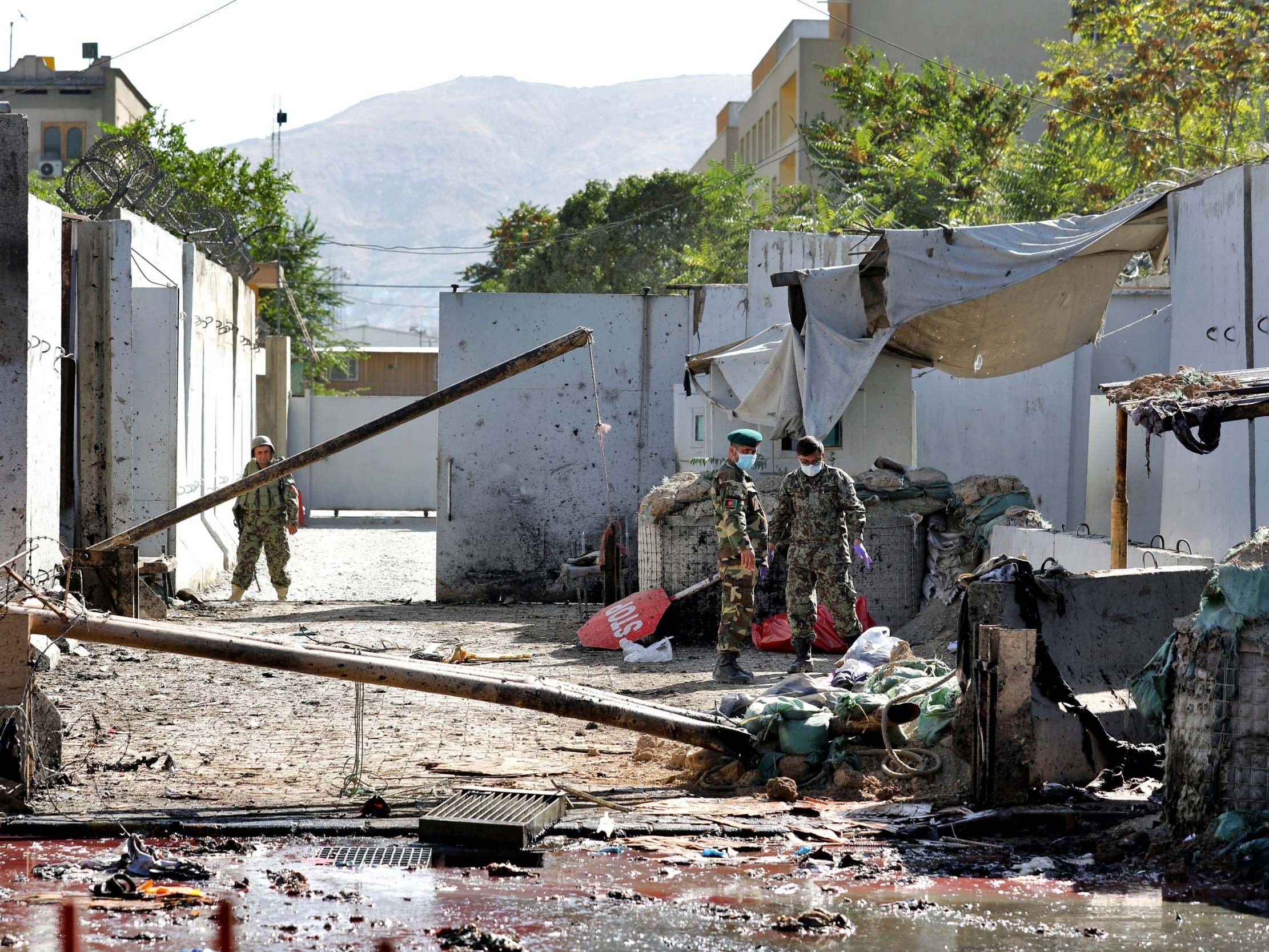 Afghan security forces work at the site of a suicide attack near the US Embassy in Kabul, Afghanistan, hours after a suicide bomb hit the president’s campaign rally.