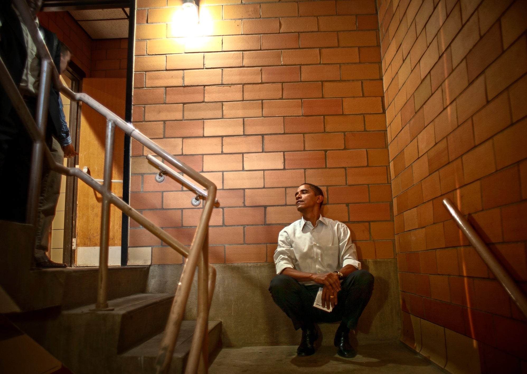 Obama listens from a back stairwell as he is introduced. It was his second or third speech of the day