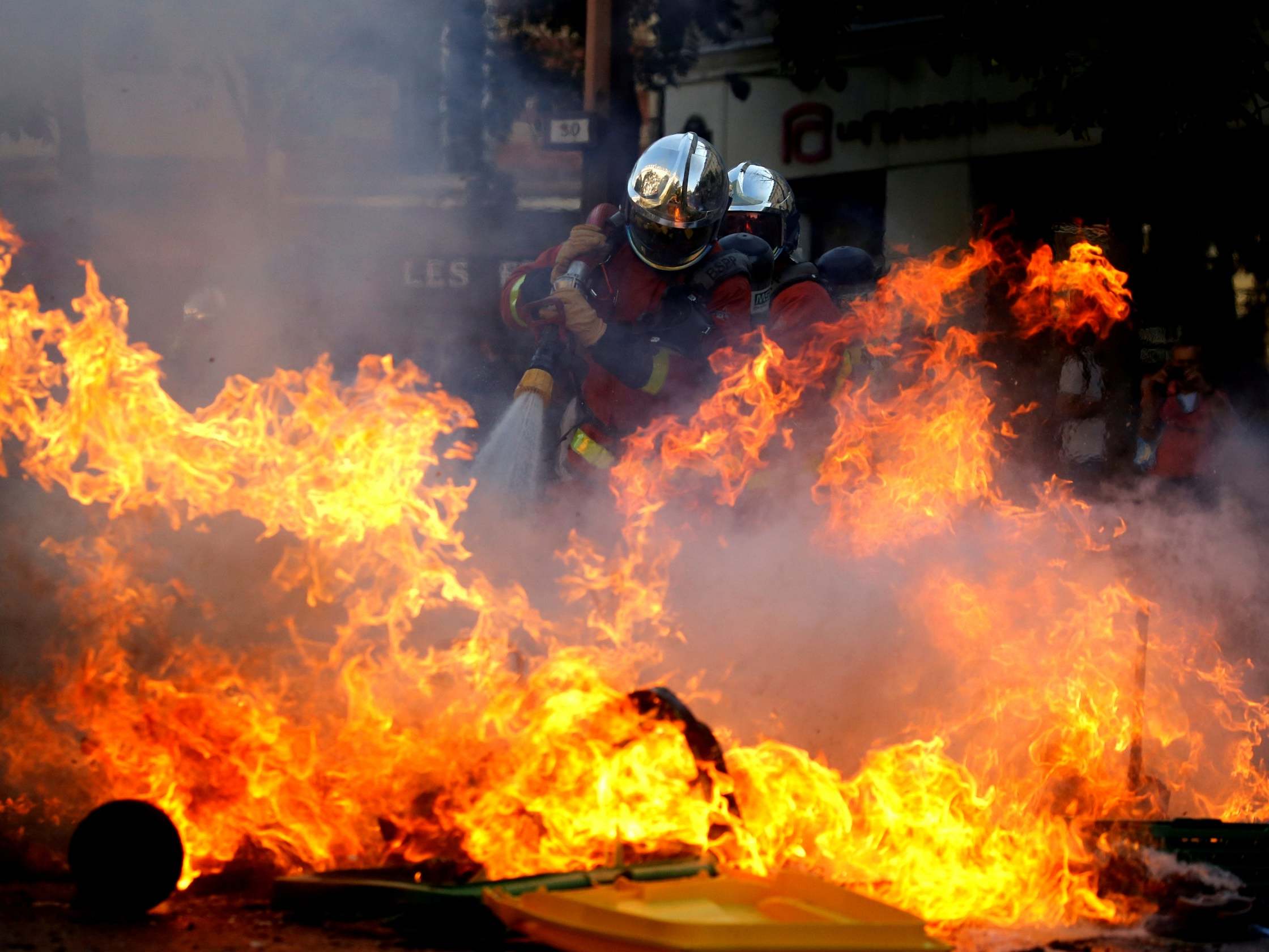 Firefighters extinguish a barricade during a protest over climate change in Paris