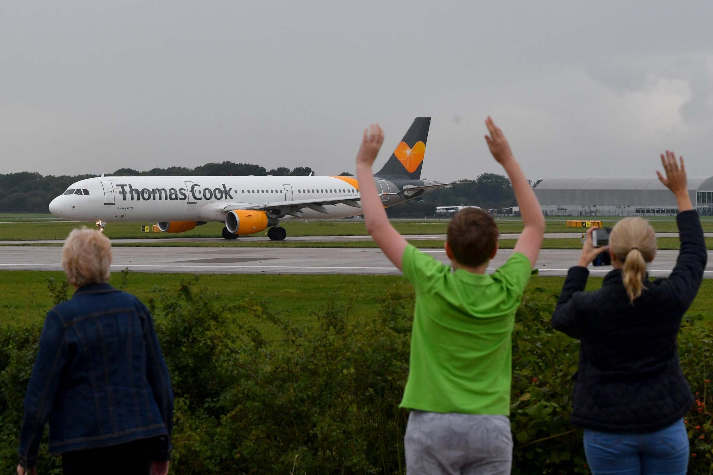 A pilot's family wave as a Thomas Cook plane departs from Manchester with the travel giant's future still uncertain