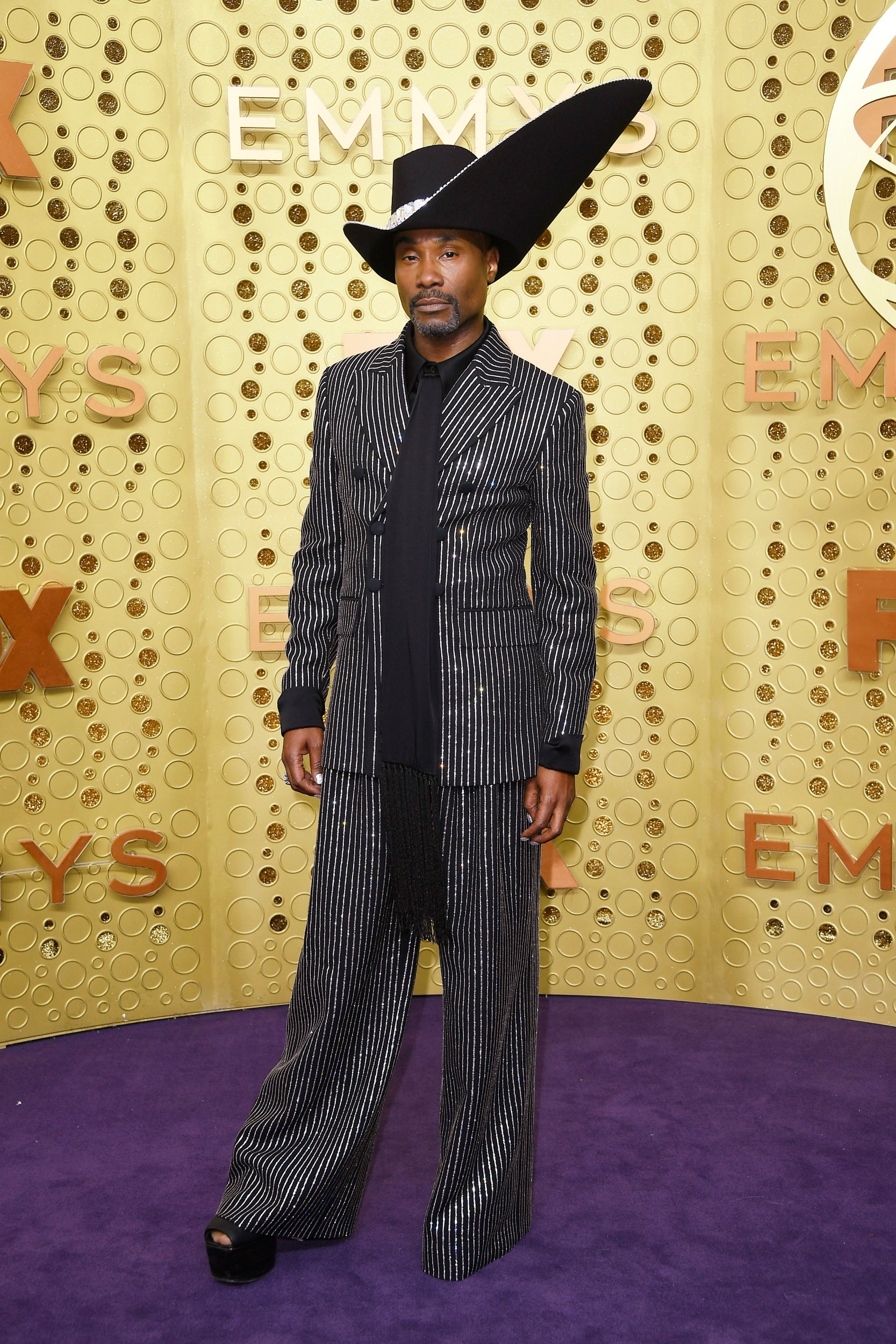 Porter makes the purple carpet his own in a pinstriped Michael Kors suit and an extravagant headpiece by milliner Stephen Jones.