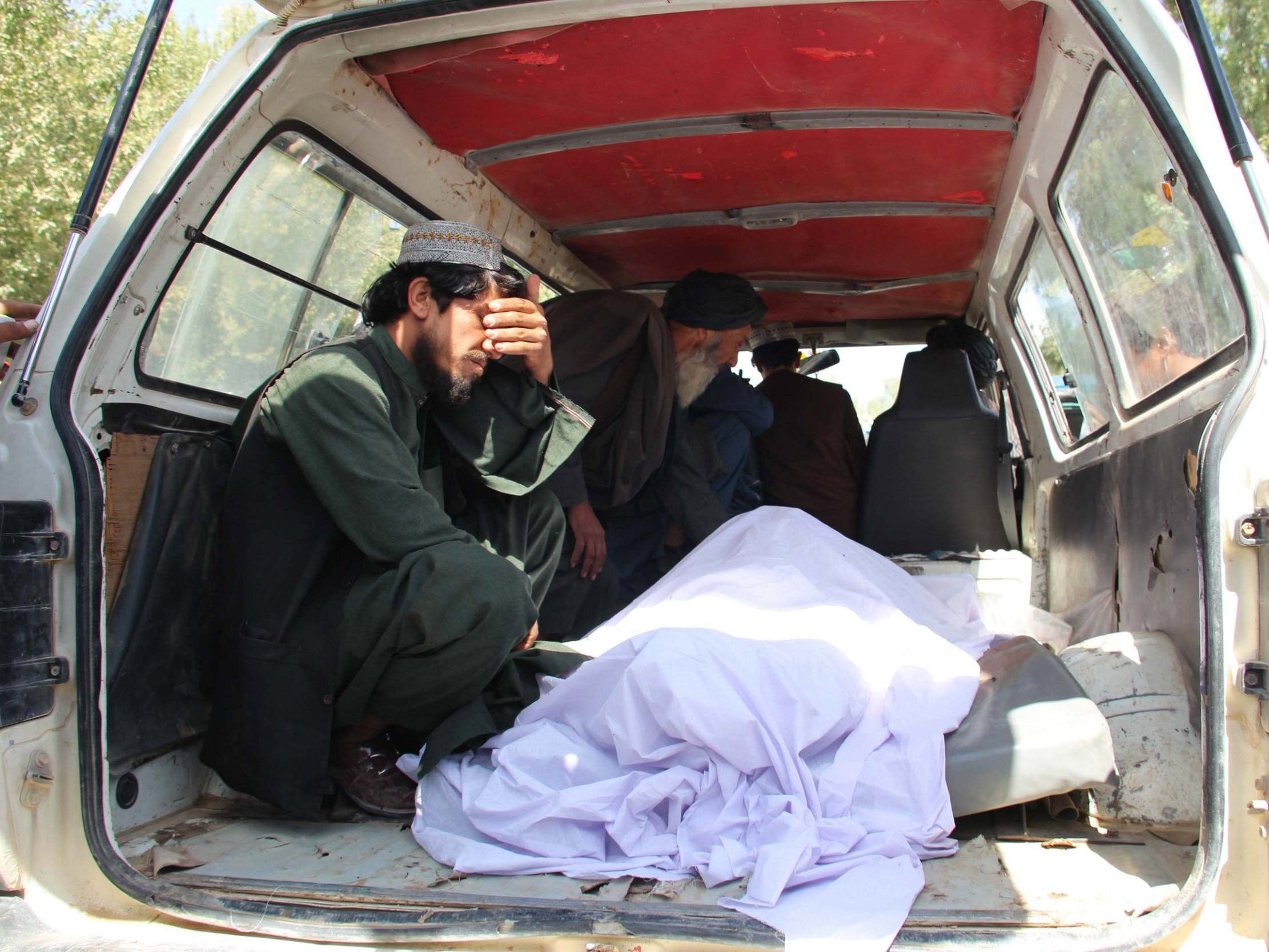 People react beside the bodies of their relatives who were killed in an air raid and ground assault on a Taliban hideout by Afghan special forces, in Helmand