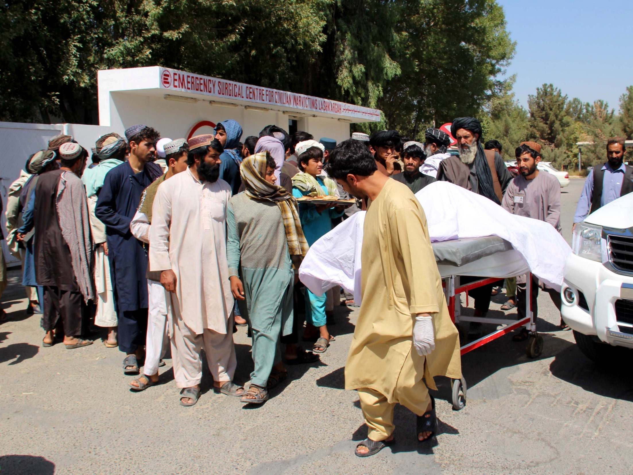 Afghan villagers carry a dead body on a stretcher outside a hospital following an airstrike in Lashkar Gah (AFP/Getty)