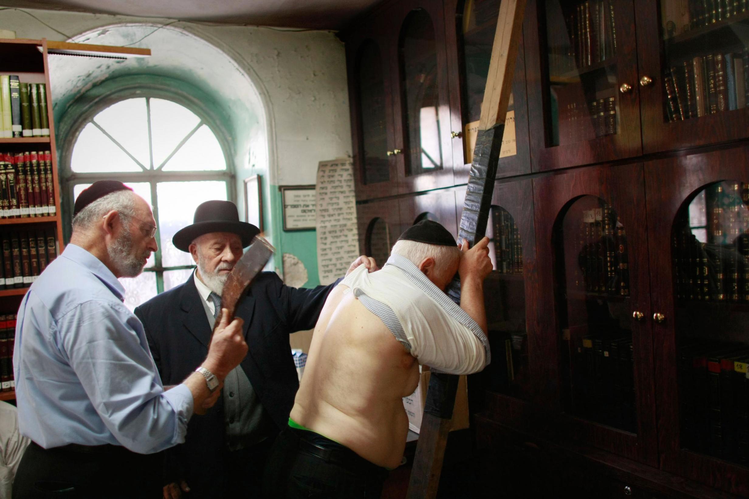 An ultra-Orthodox Jewish man whips another with a leather strep as a symbolic punishment for his sins during the traditional Malkot ceremony, just hours before the start of Yom Kippur, at a synagogue in Jerusalem