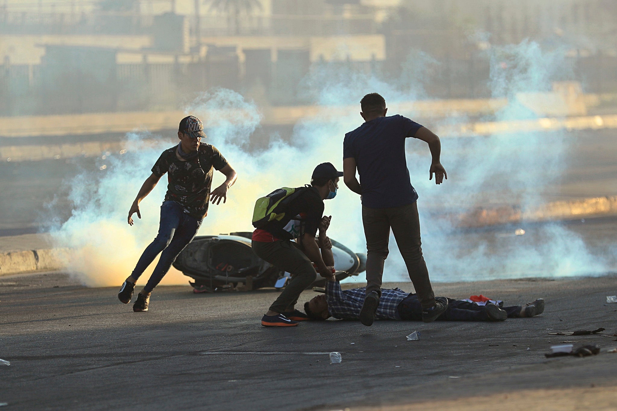 Anti-government protesters rush to an injured protestor during a demonstration in Baghdad