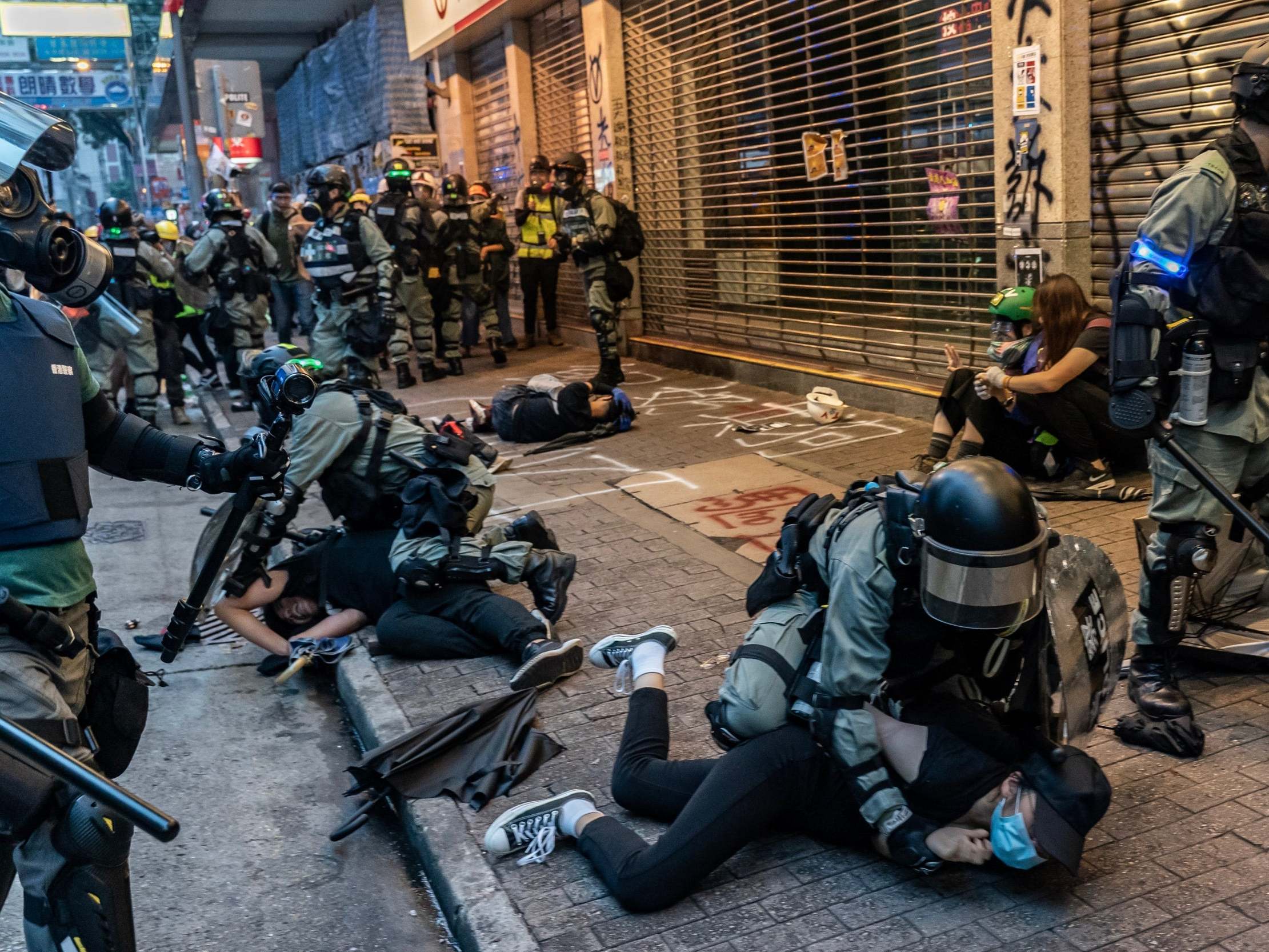 Police detain a protester on Sunday, before the former British governor warned armed police would likely soon lead to deaths