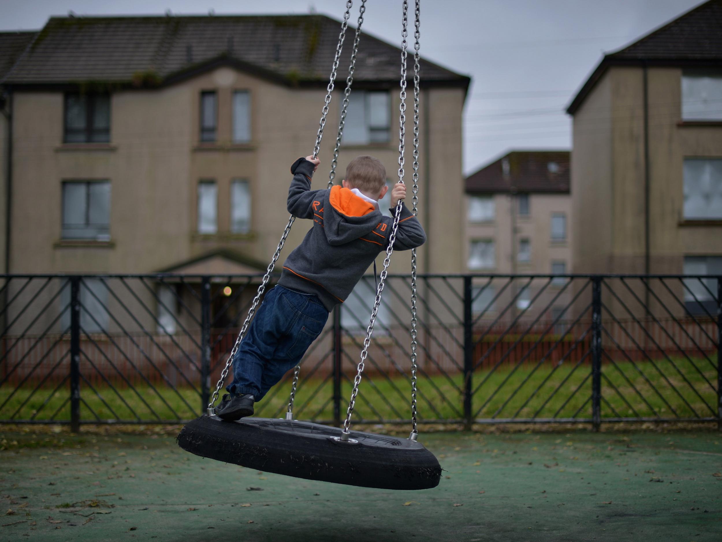 A young boy plays in a play park near disused housing in the Hamiltonhill area of Glasgow