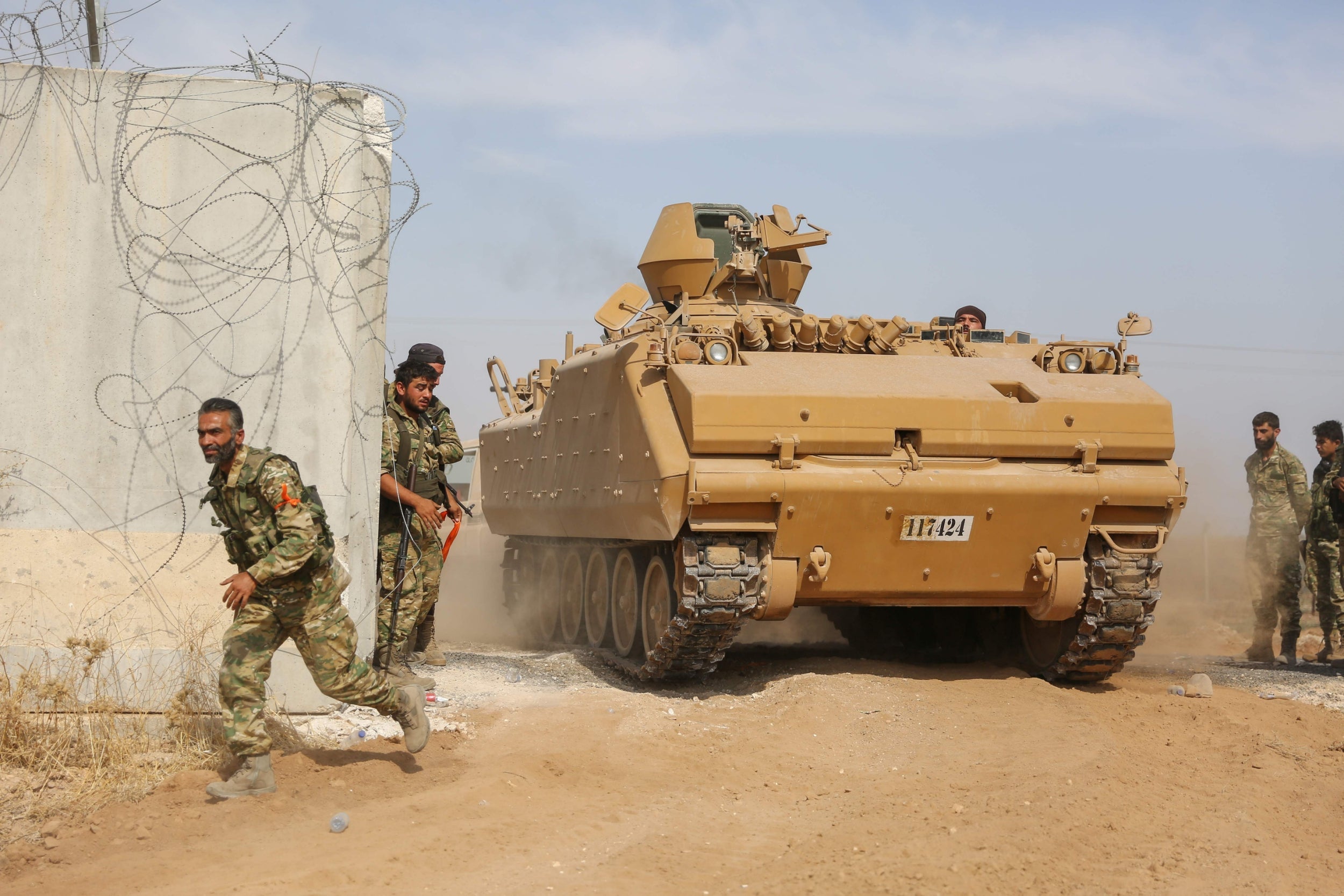 Pro-Turkish Syrian fighters drive an armoured personnel carrier across the border into Syria