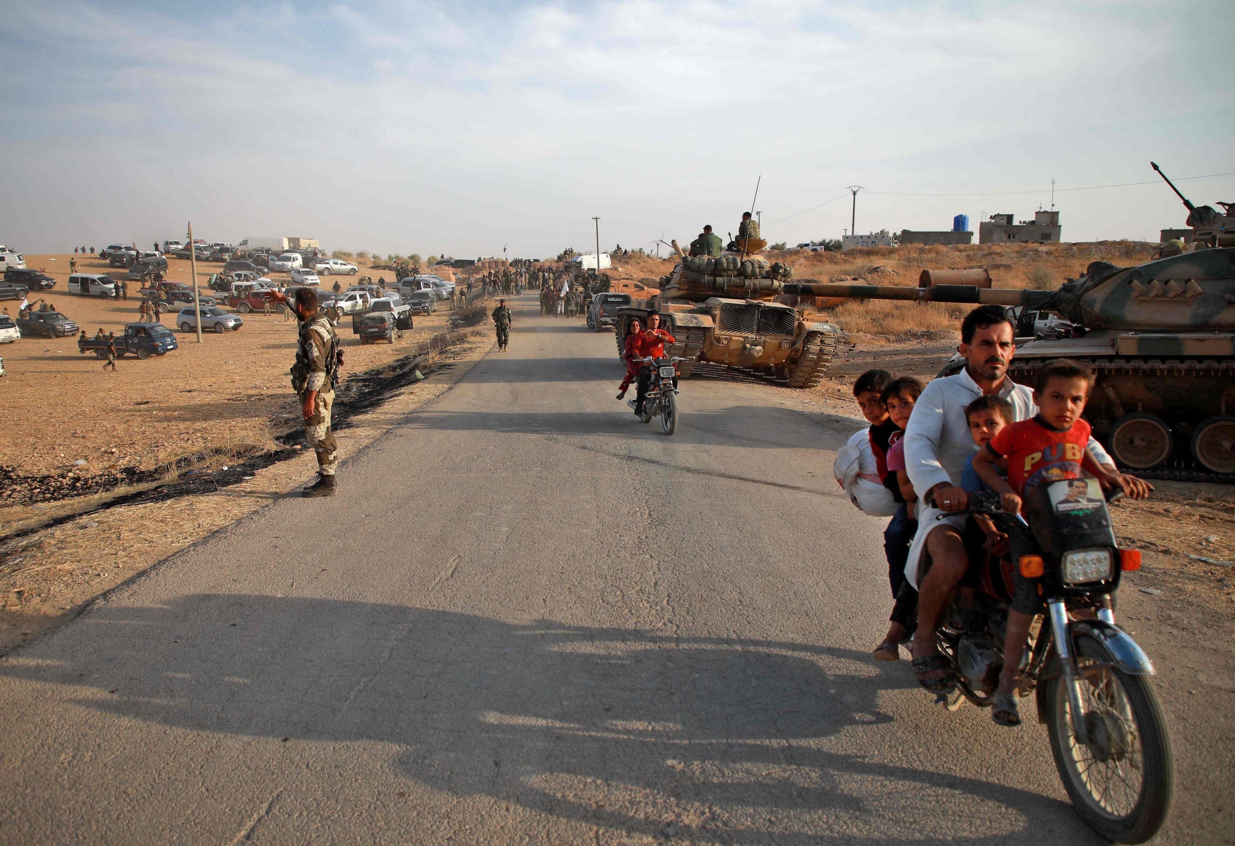 Civilians flee as Turkish troops with American-made tanks and Turkish-backed Syrian fighters gather near the village of Qirata (AFP/Getty)