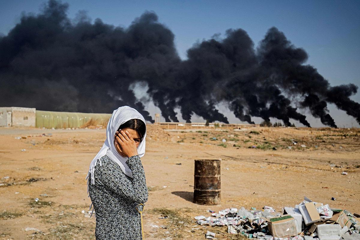 A woman stands on the outskirts of the town of Tal Tamr near the Syrian Kurdish town of Ras al-Ayn, where Turkish forces have aimed attacks