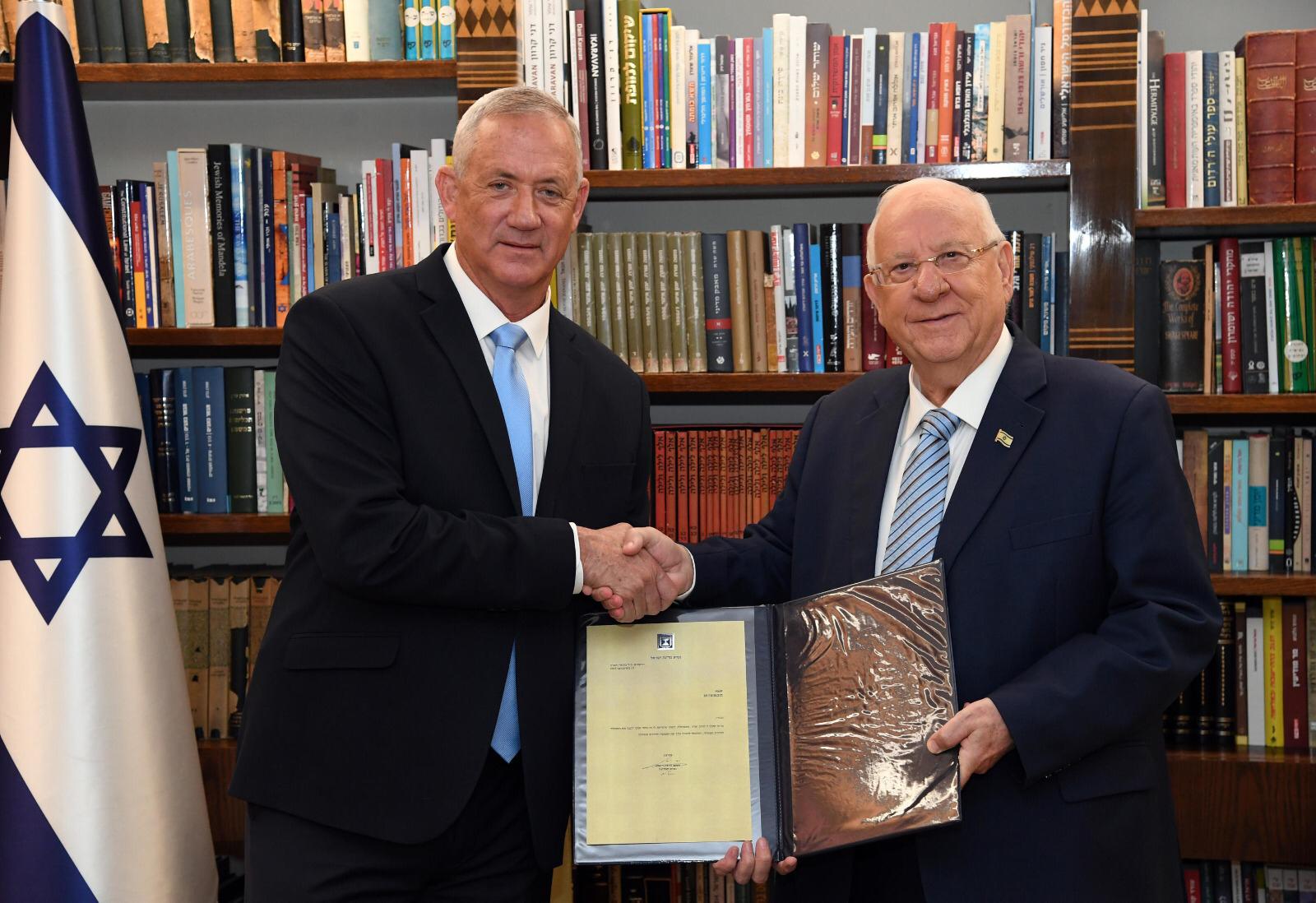 Ex-army chief Benny Gantz shakes hands with President Reuven Rivlin after he is tasked with trying to form the next Israeli government