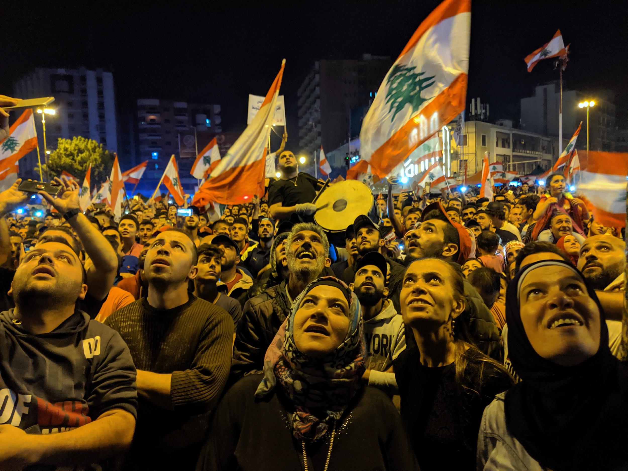 Protesters in Nour Square, Tripoli, stare up at a DJ playing music from a balcony in an abandoned building. Tens of thousands of people have filled the square every night this week