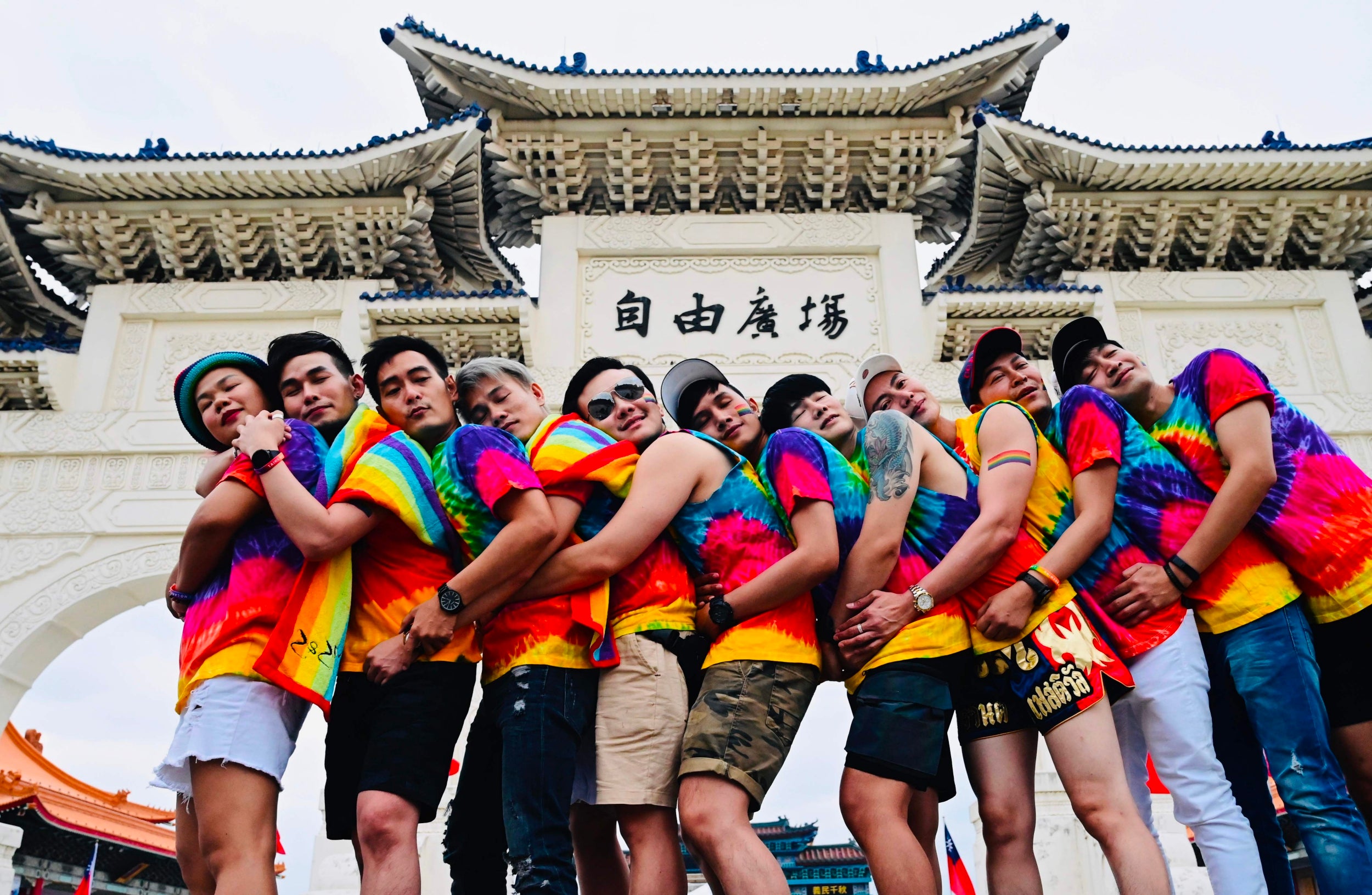 Parade-goers pose in front of the Chiang Kai-shek Memorial Hall in matching rainbow-coloured tops