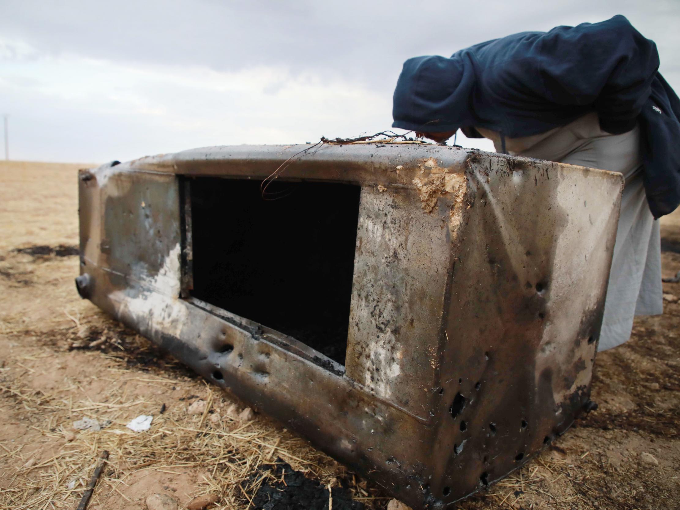 A Syrian man looks inside a metal container where a charred body was found at the spot where Abu Hassan al-Muhajir was reportedly killed