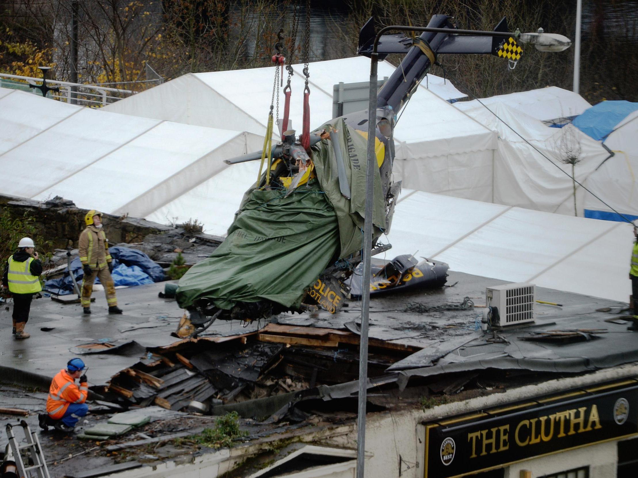 Rescuers lift the police helicopter wreckage from the roof of the The Clutha