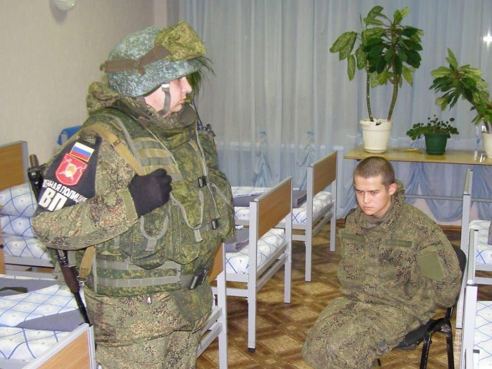 Ramil Shamsutdinov (right) is guarded by an officer after arrest