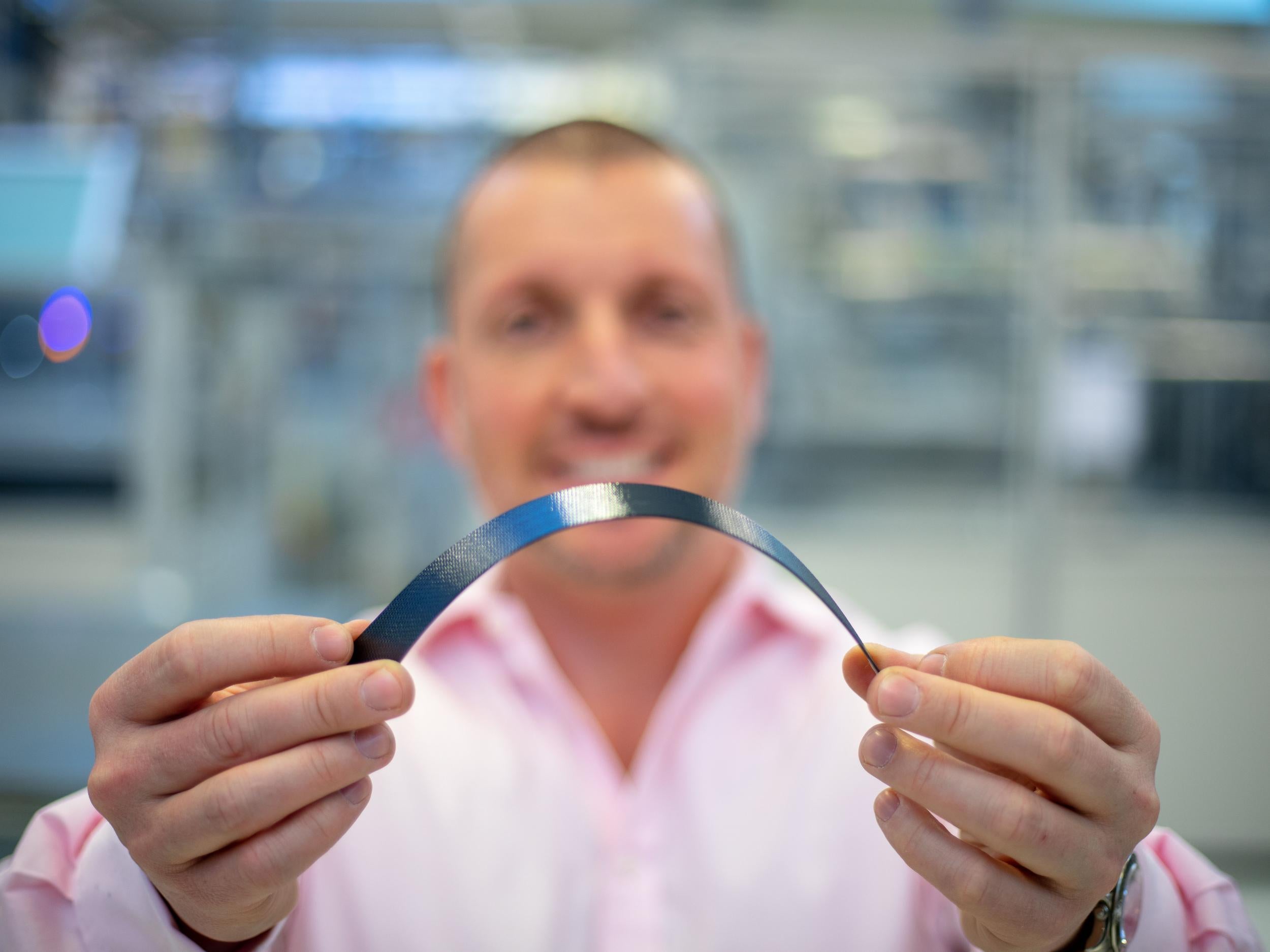 Fili holding up a solar cell that will be attached to wireless headphones