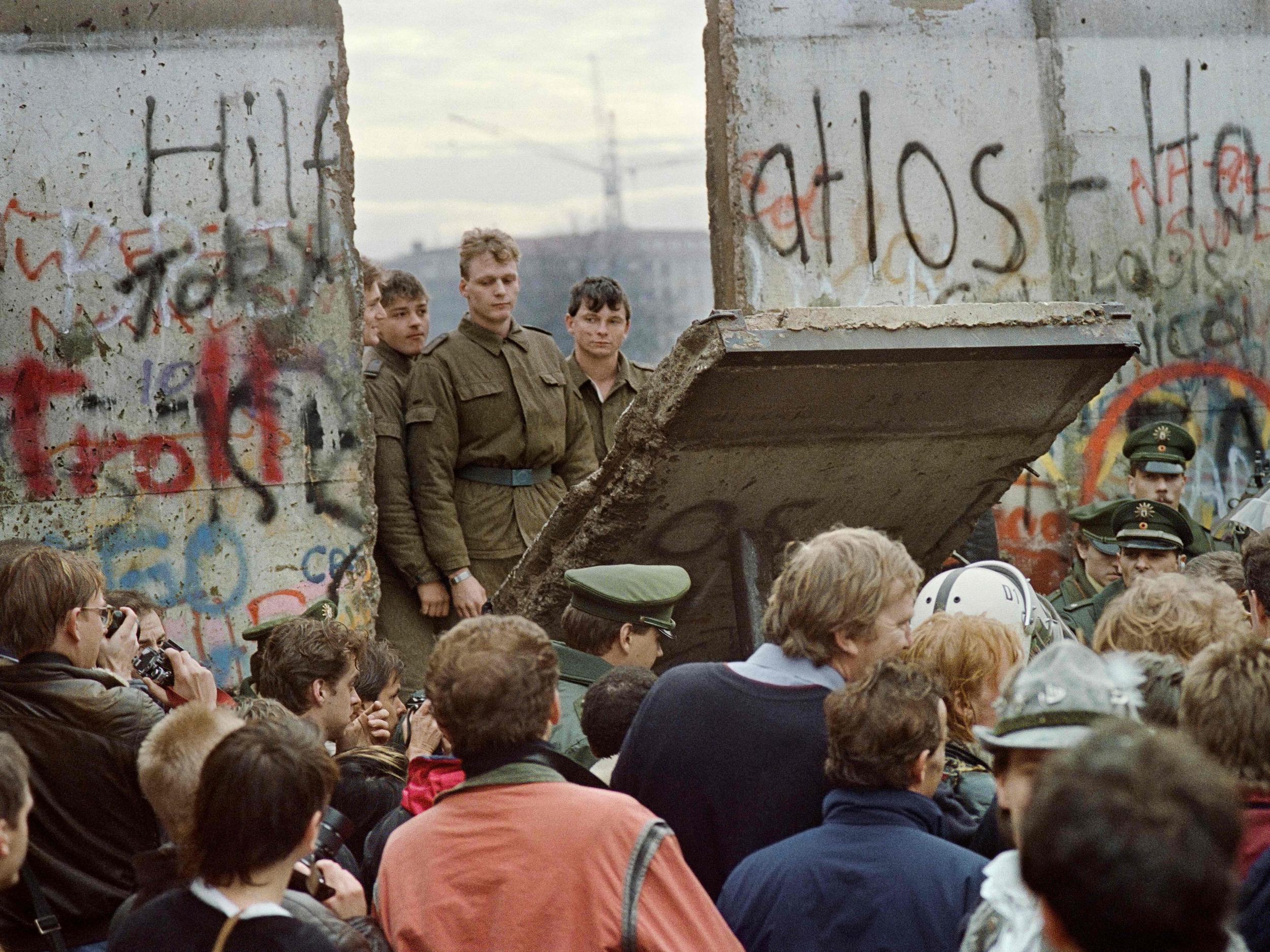 East German border guards demolish a section of the wall to open a new crossing point between East and West Berlin on 11 November 1989