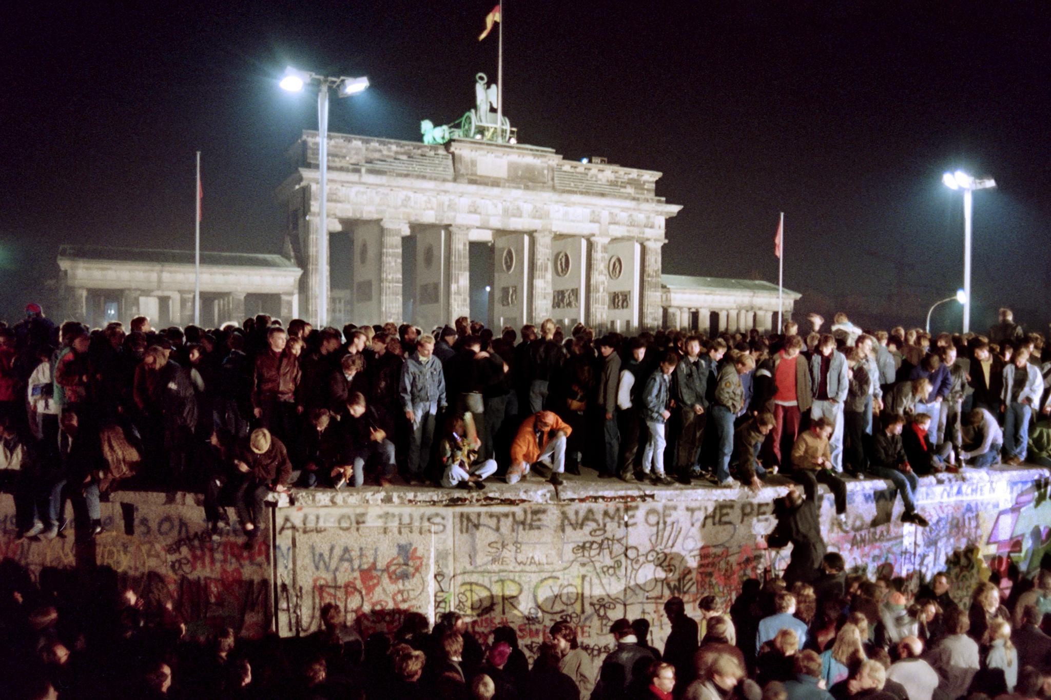 Young East Berliners stand on top of the wall on 11 November 1989