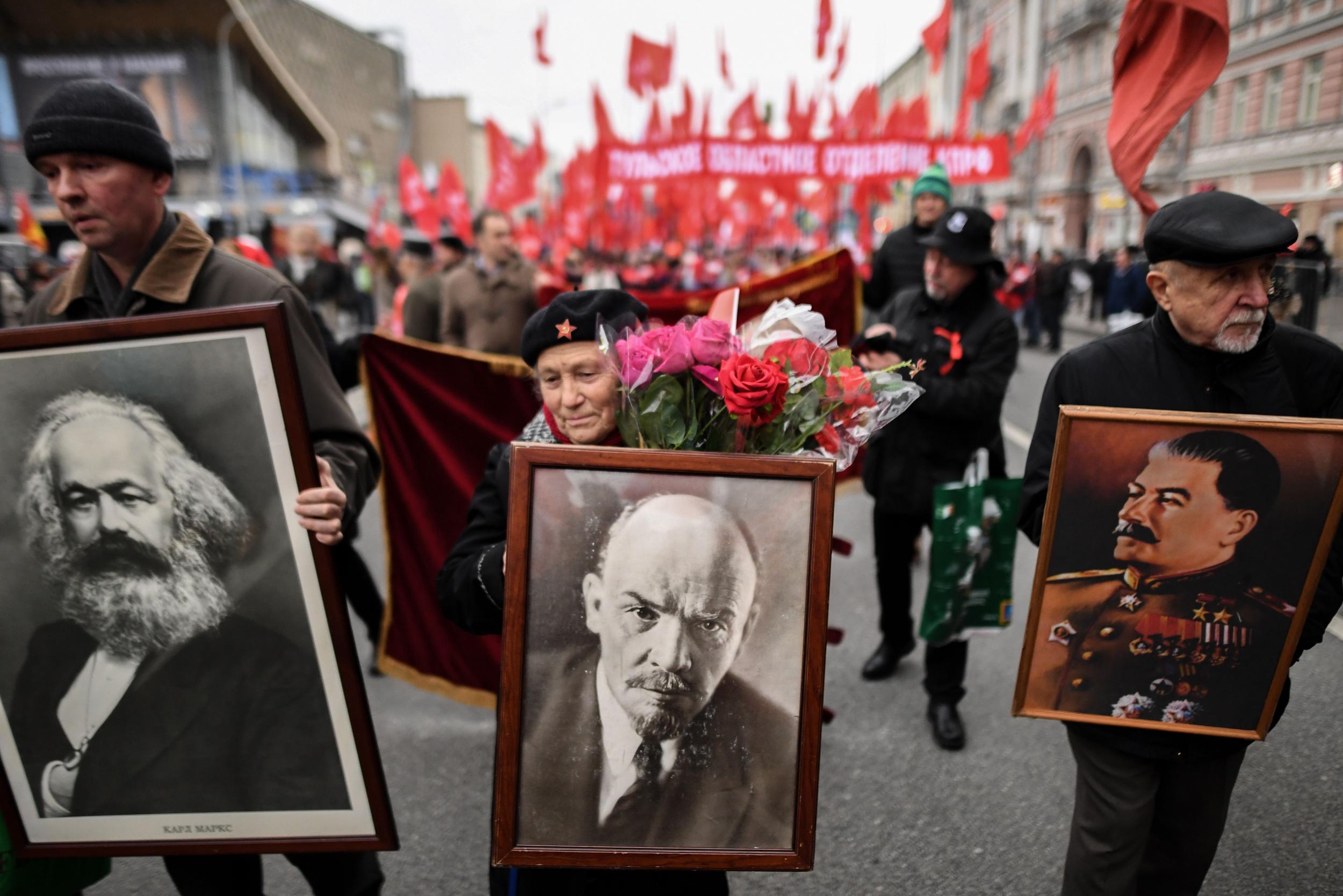 Russian Communist supporters holding portraits of Karl Marx, Vladimir Lenin and Joseph Stalin participate in a rally marking the anniversary of the 1917 Bolshevik Revolution in downtown Moscow