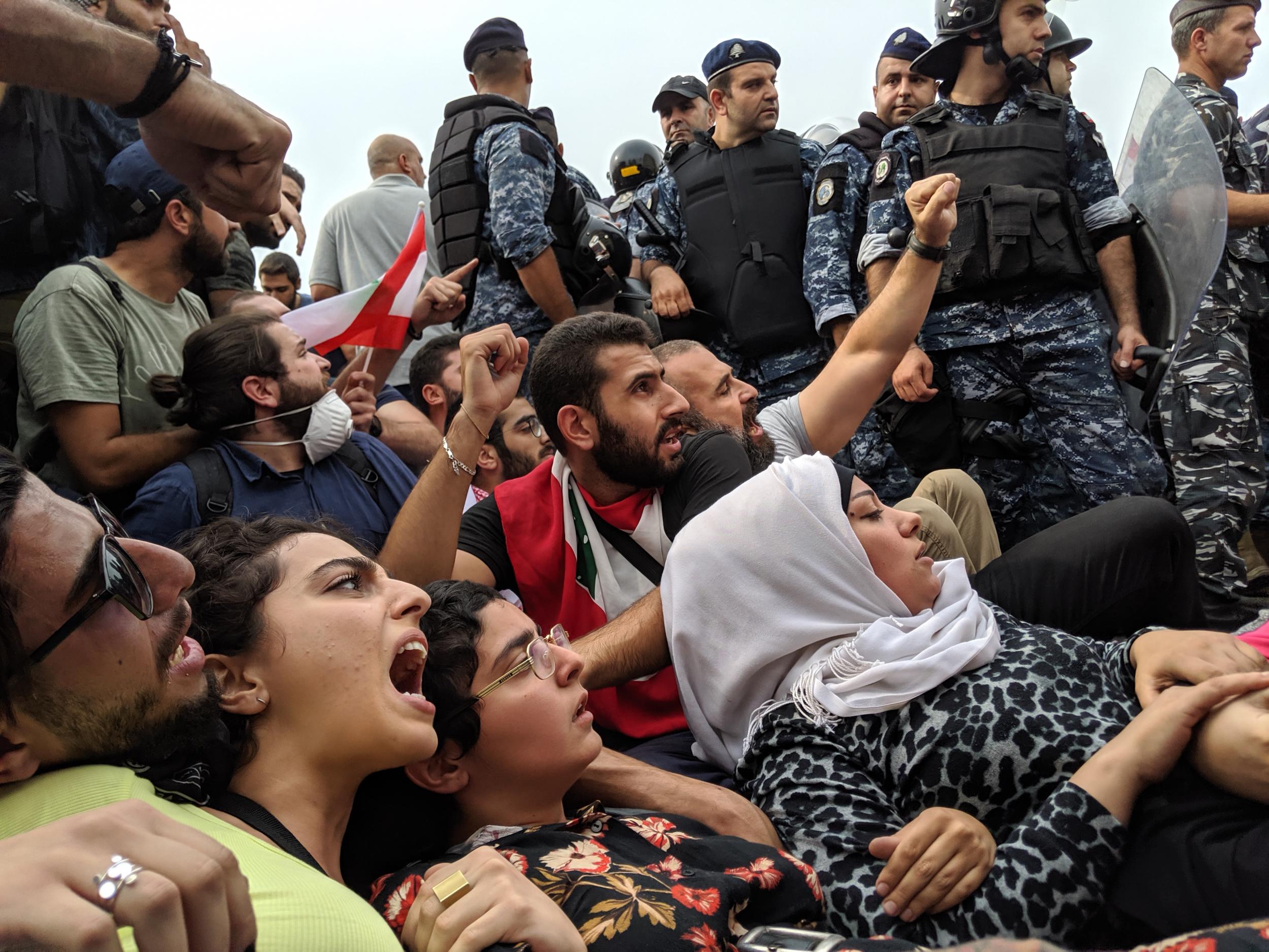 A group of women resist police attempts to clear a sit-in that is blocking a road through Beirut during anti-government demonstrations (Richard Hall/The Independent)