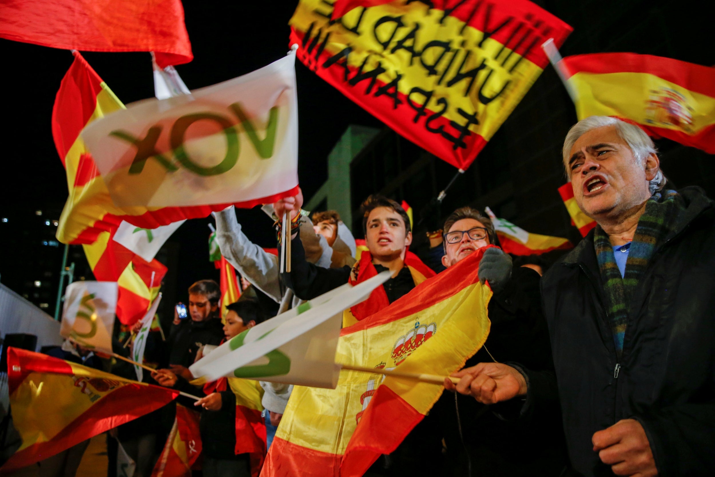 Supporters of Spain’s far-right party VOX react as they hold flags during Spain’s general election, outside the party headquarters in Madrid, Spain