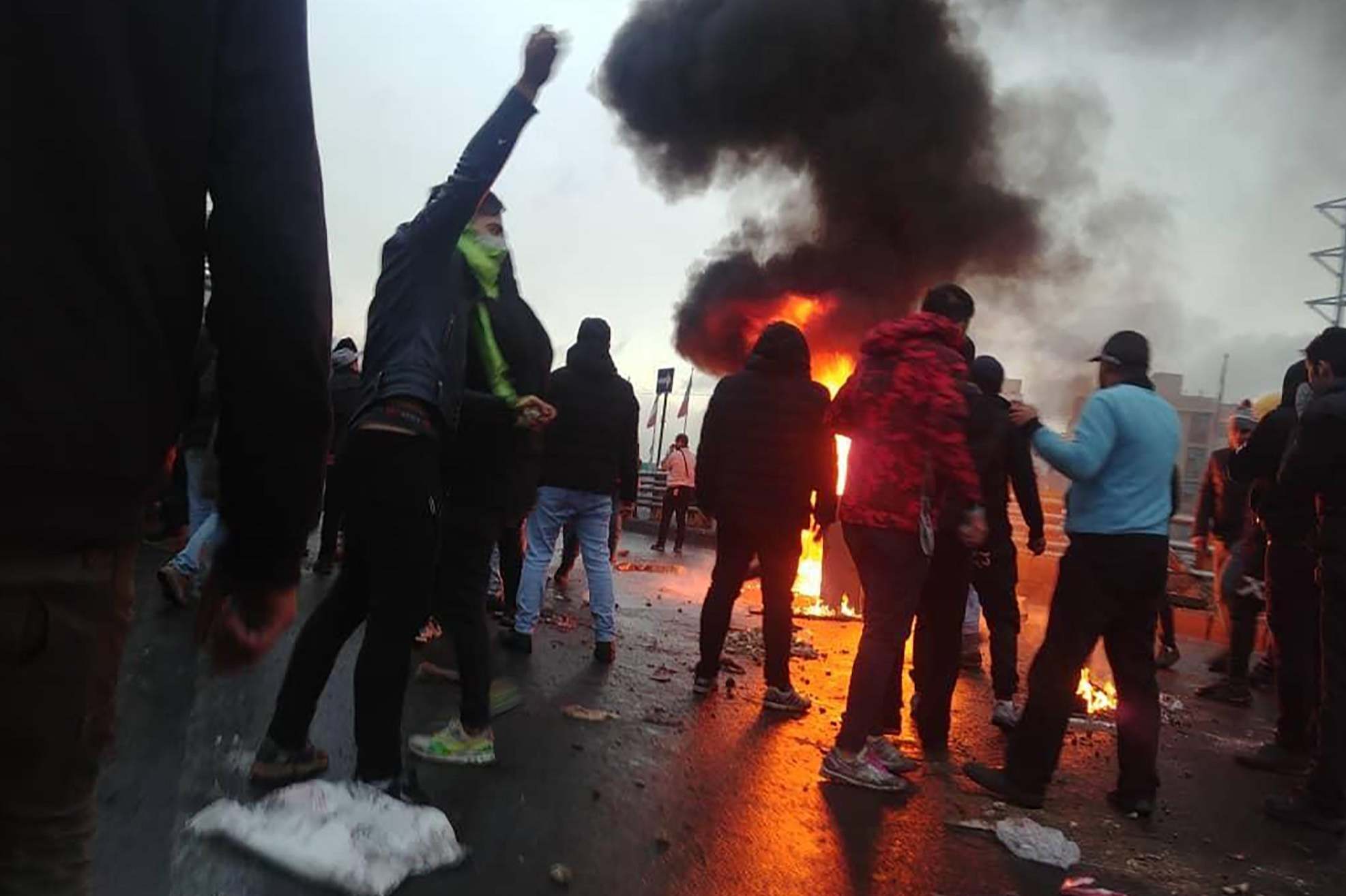 Iranian protesters gather around a fire during a demonstration against an increase in gasoline prices in the capital Tehran at the weekend