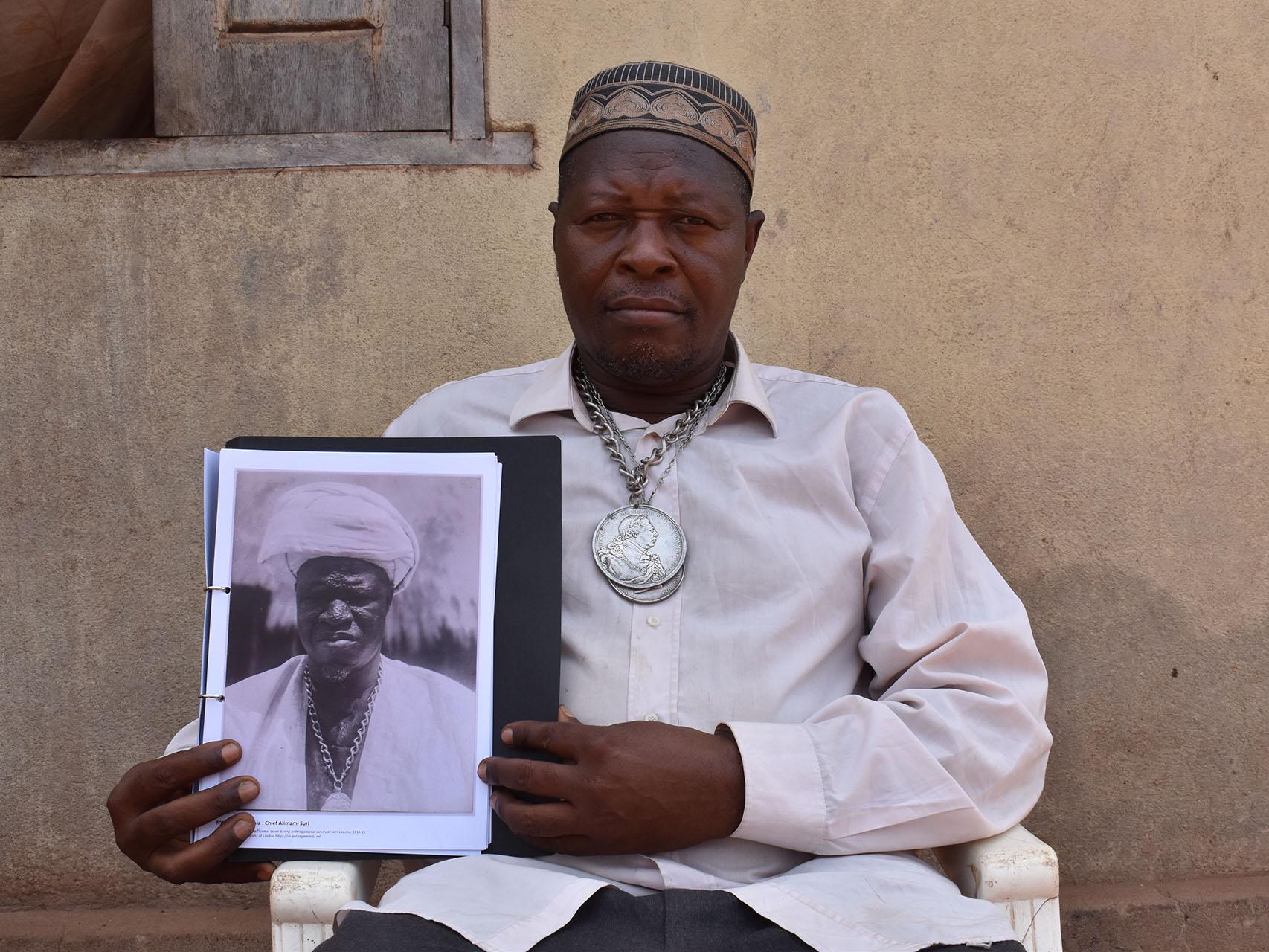 Paramount chief Kandeh Sorie Kakanday III with Northcote Thomas's photograph of his ancestor Almamy Suri Kakandeh in Sierra Leone