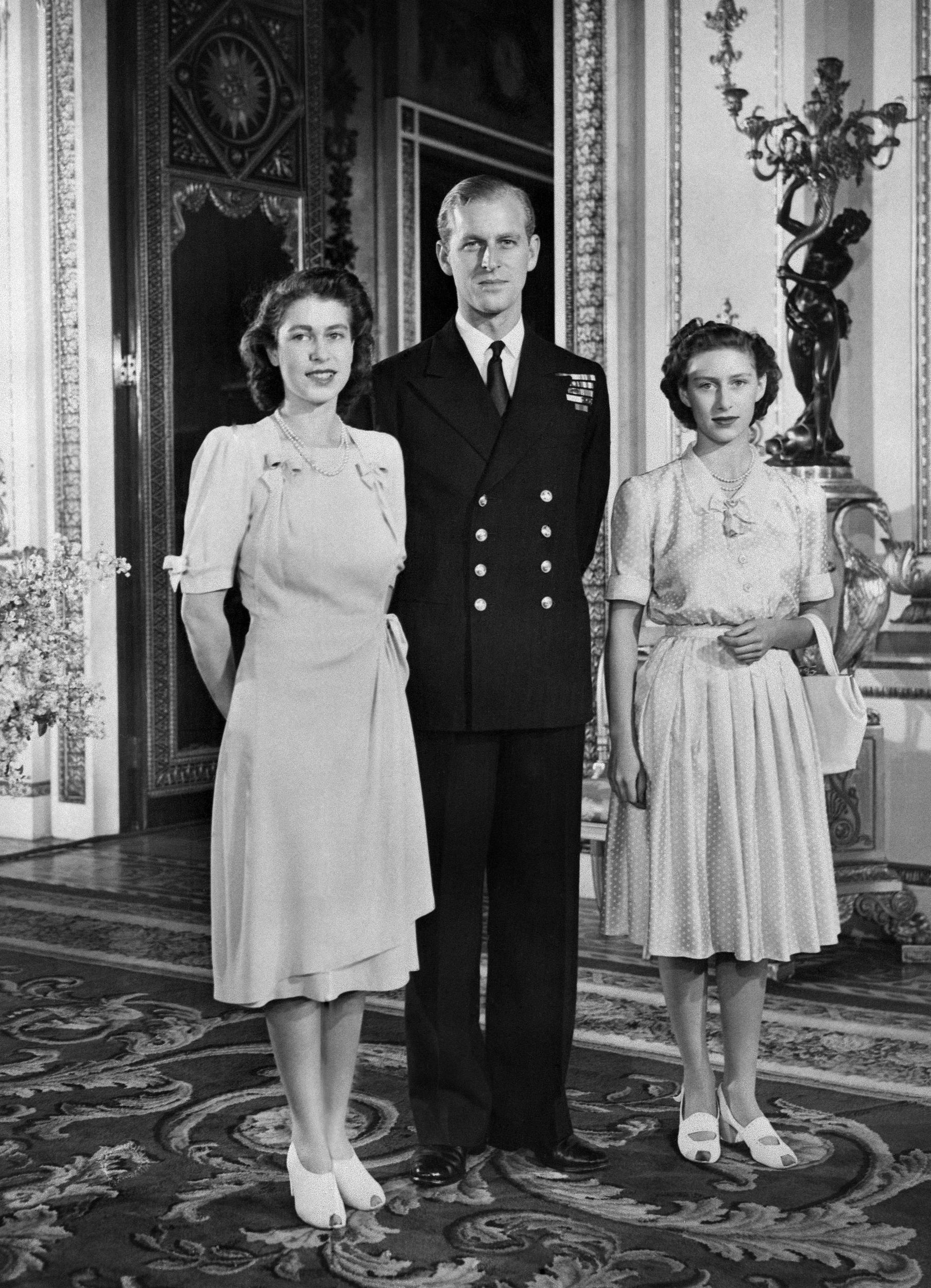 The then-Princess Elizabeth and Philip Mountbatten pose for a photograph on the day their engagement is announced alongside Princess Margaret (9 July 1947)
