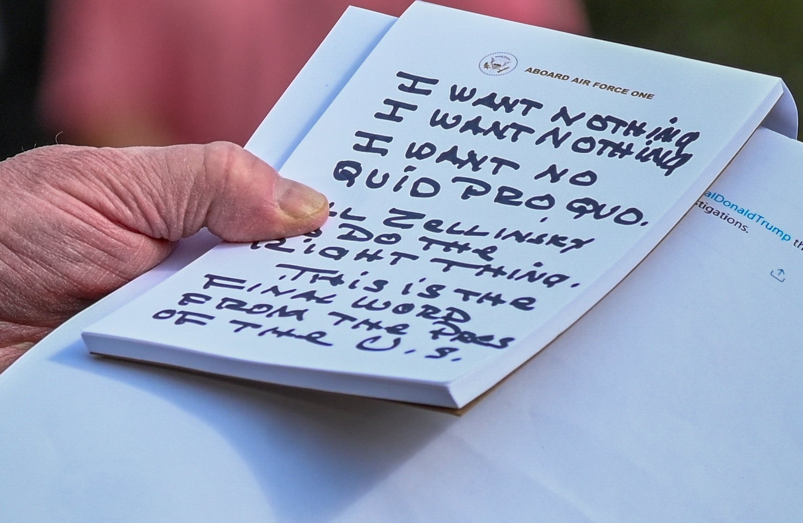 Donald Trump holds notes reading 'I WANT NOTHING. I WANT NOTHING. I WANT NO QUID PRO QUO' as he speaks to reporters outside the White House