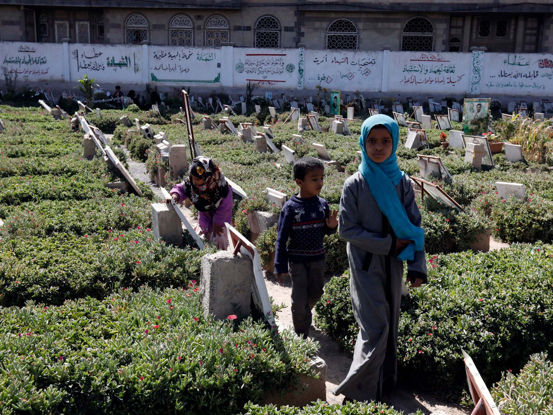 Yemeni children walk among the graves of people killed in a war that has claimed the lives of 100,000 since 2015