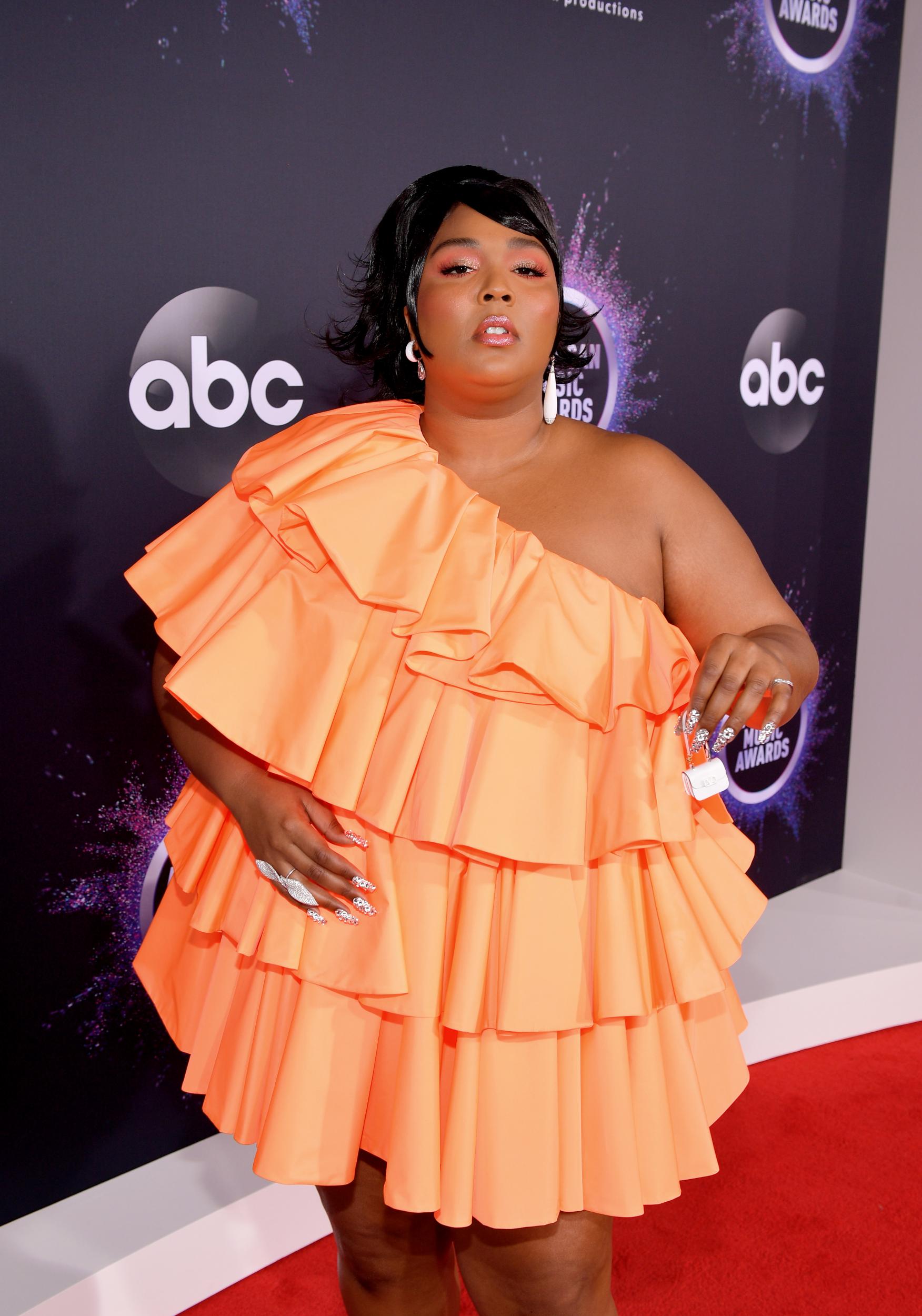 The 'Truth Hurts' singer proved that even the tiniest of accessories can pack a fashion punch with this minuscule white purse. The custom Valentino look   featured an off-shoulder tangerine gown complete with layers of ruffles, but it is the handbag that will have fans fawning over Lizzo's outfit.