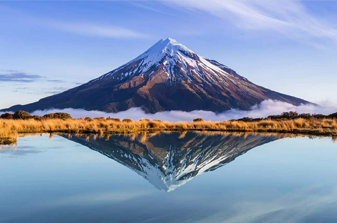 ‘Mount Taranaki, New Zealand’ by @superthijs shows Mount Taranaki in New Zeland reflected in a lake