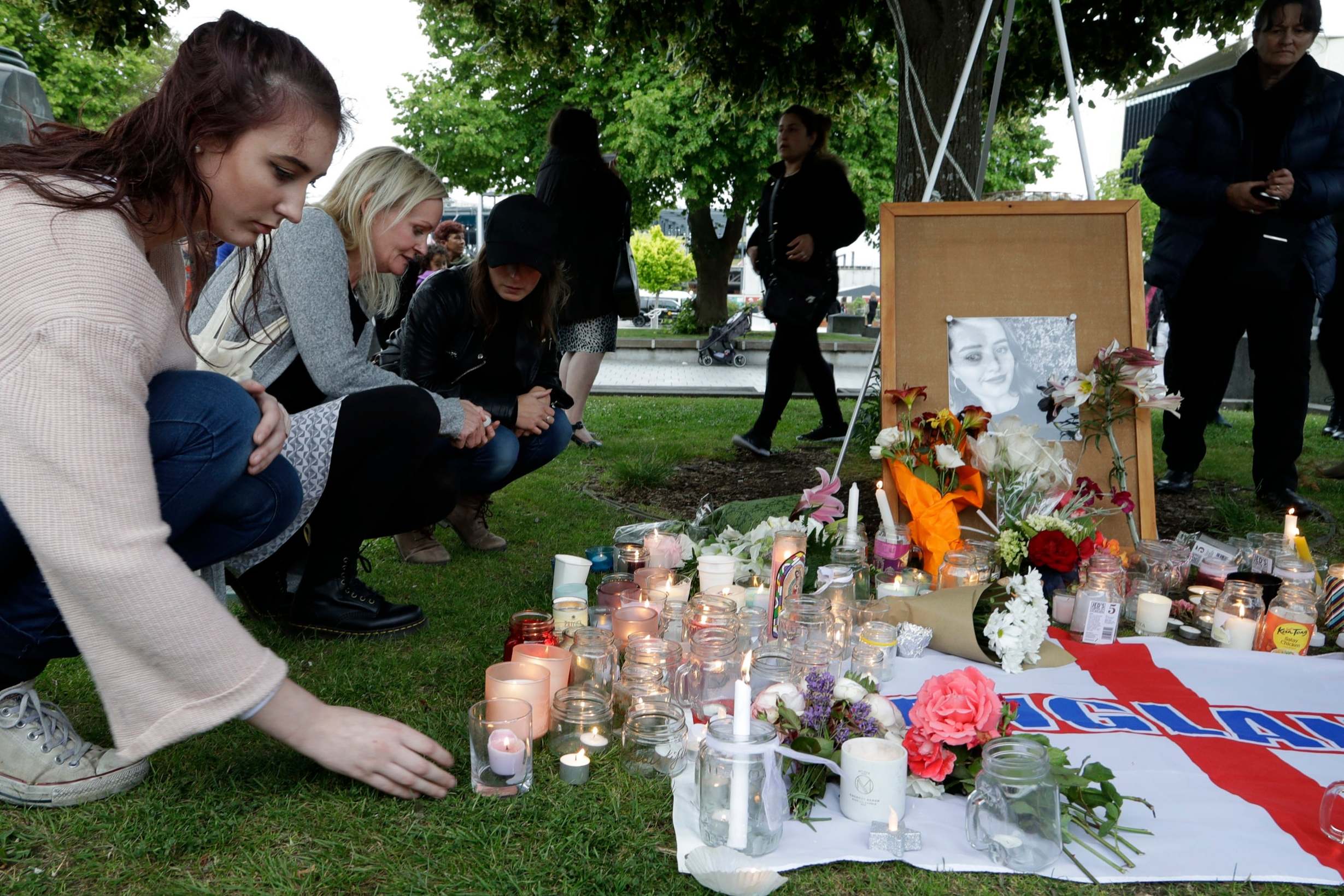 People lay flowers and light candles during a candlelight vigil for Millane in Christchurch