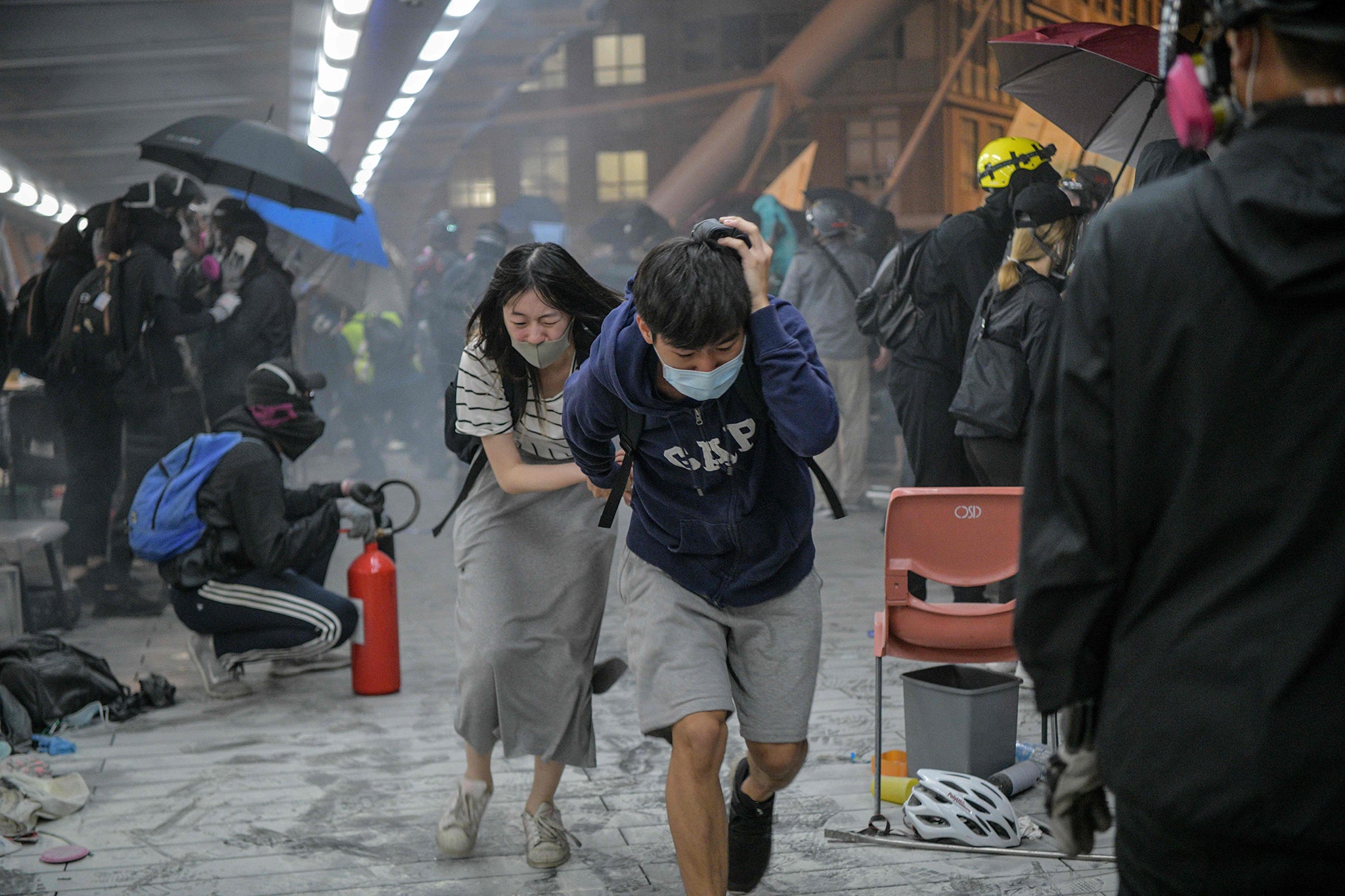 Protesters take cover after police fire teargas towards the bridge they are attempting to climb down to escape