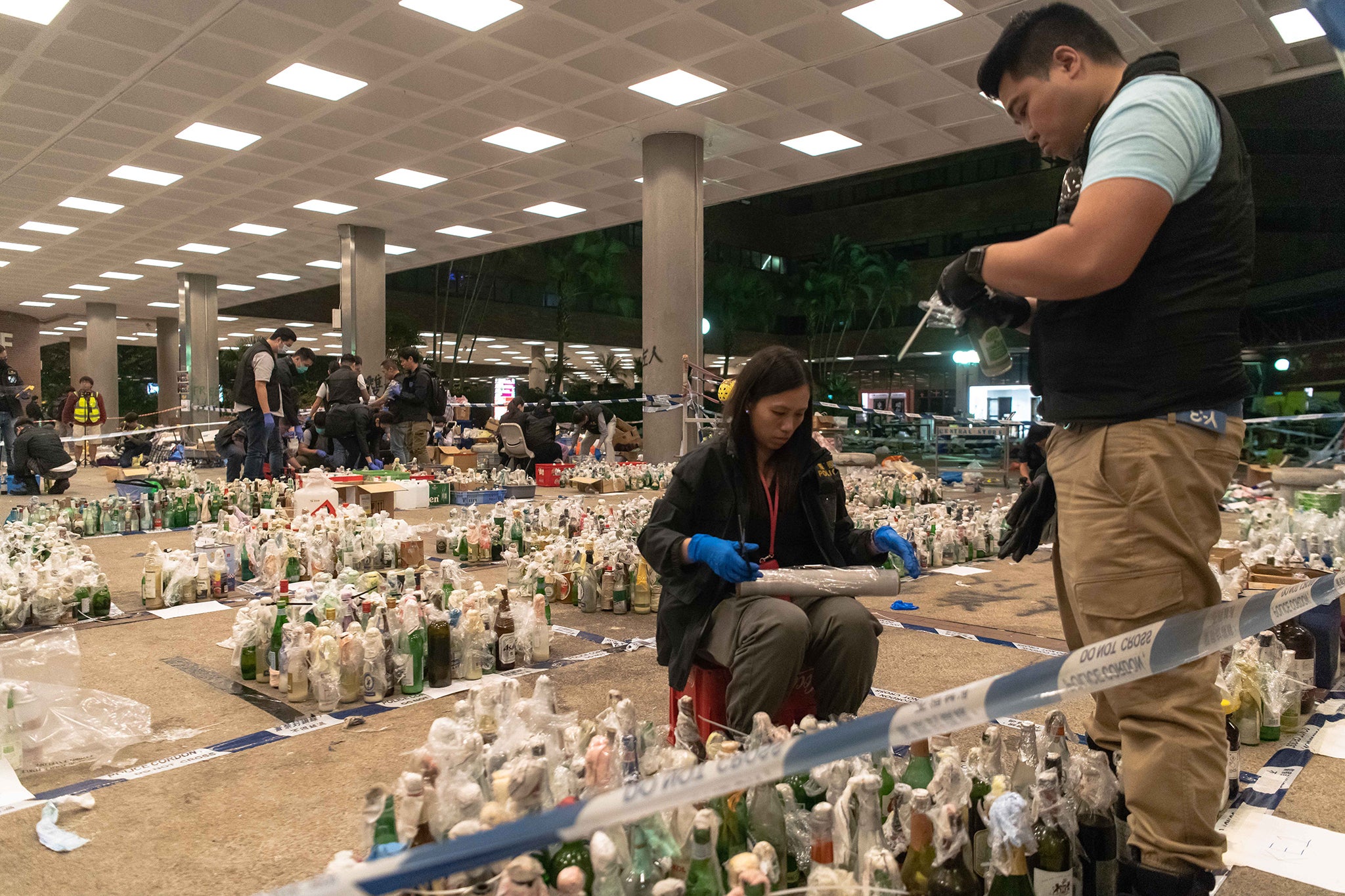 Police officers inspect and catalogue thousands of molotov cocktails left behind in PolyU