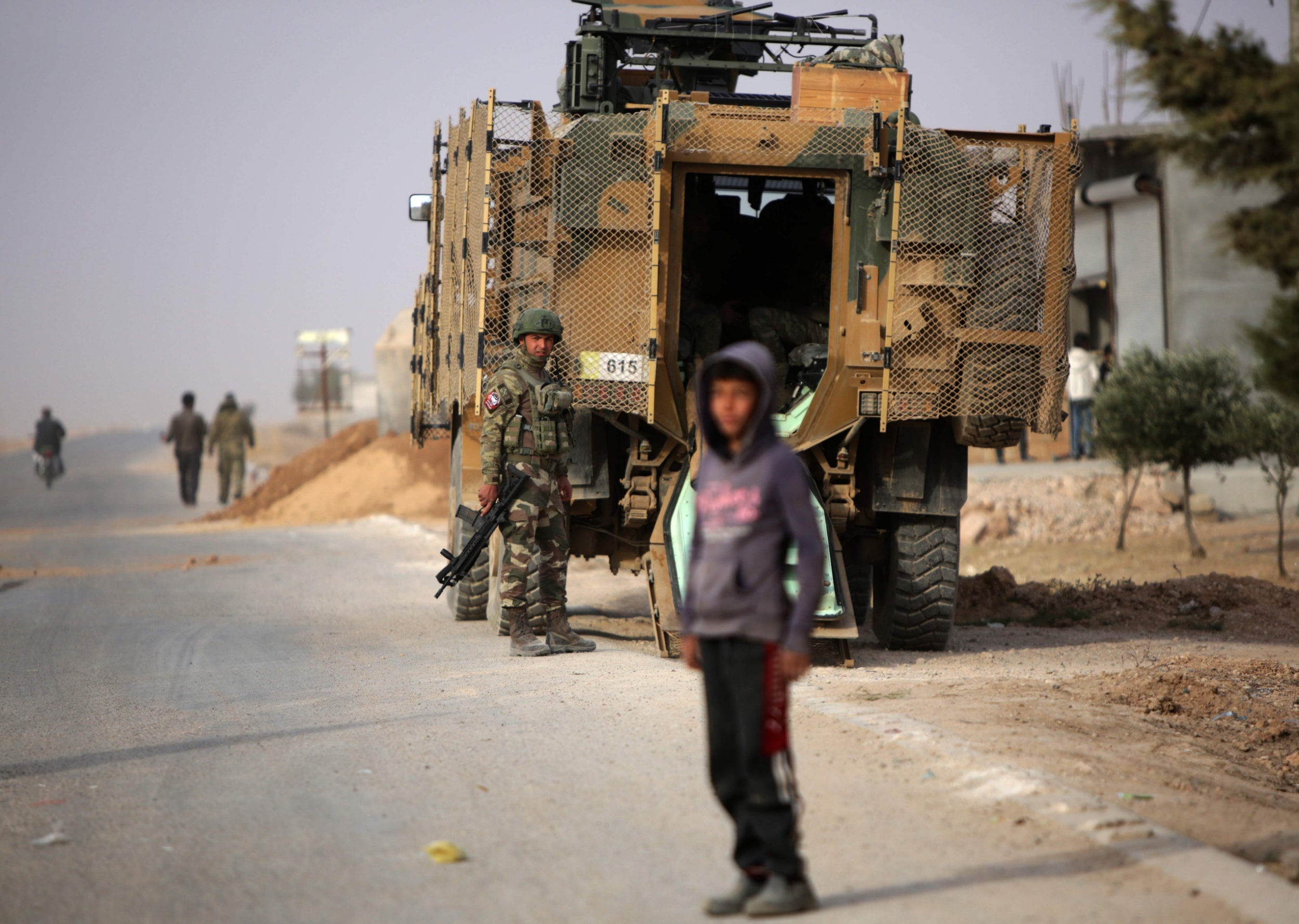 A Turkish soldier stands near his armoured vehicle on a highway near the northern Syrian town of Ain Issa in late November (AFP/Getty)