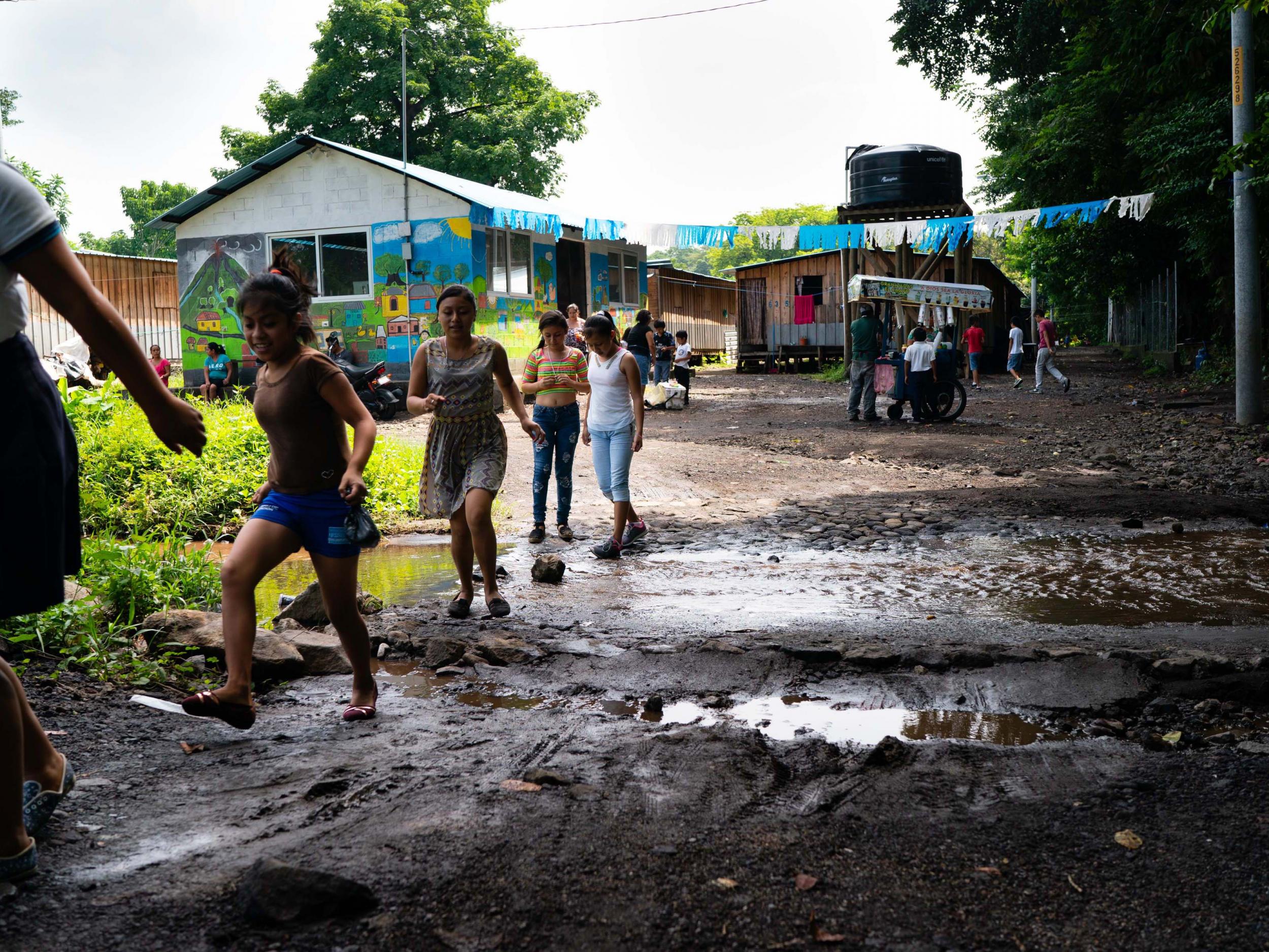 Children jump over a muddy creek during a break at school (The Washington Post)