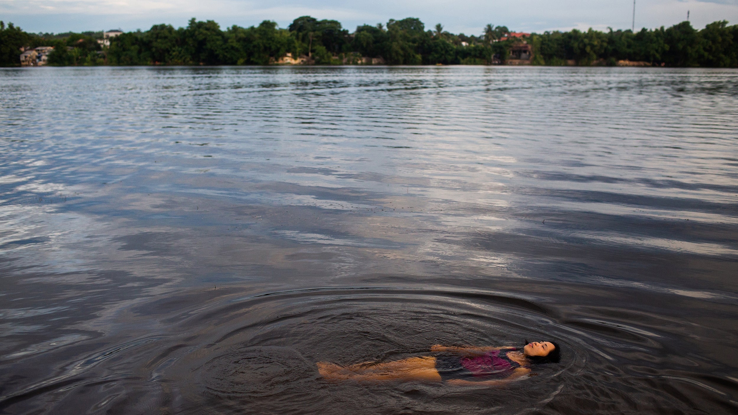 Huong Lan floats in the Huong River in Hue City. Lan has started a programme encouraging women to swim each morning and evening in the river while collecting trash, watering gardens on the riverbank and keeping their swimming area clean