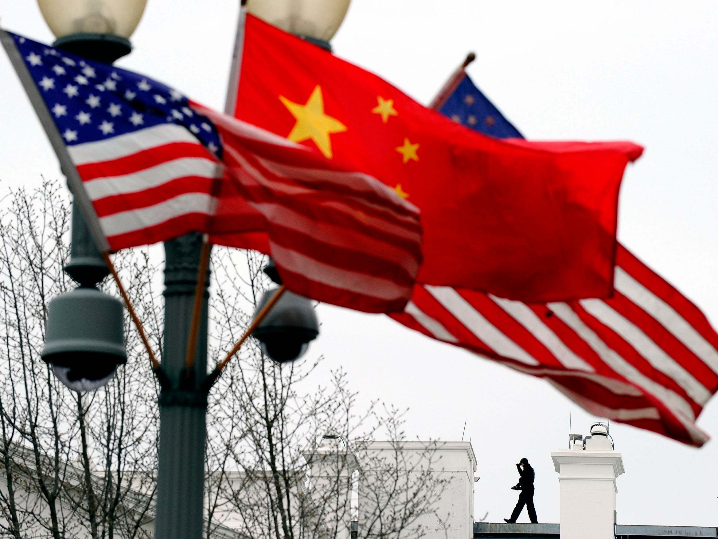 Aa Secret Service agent guards his post on the roof of the White House as a lamp post is adorned with Chinese and US national flags in Washington, DC