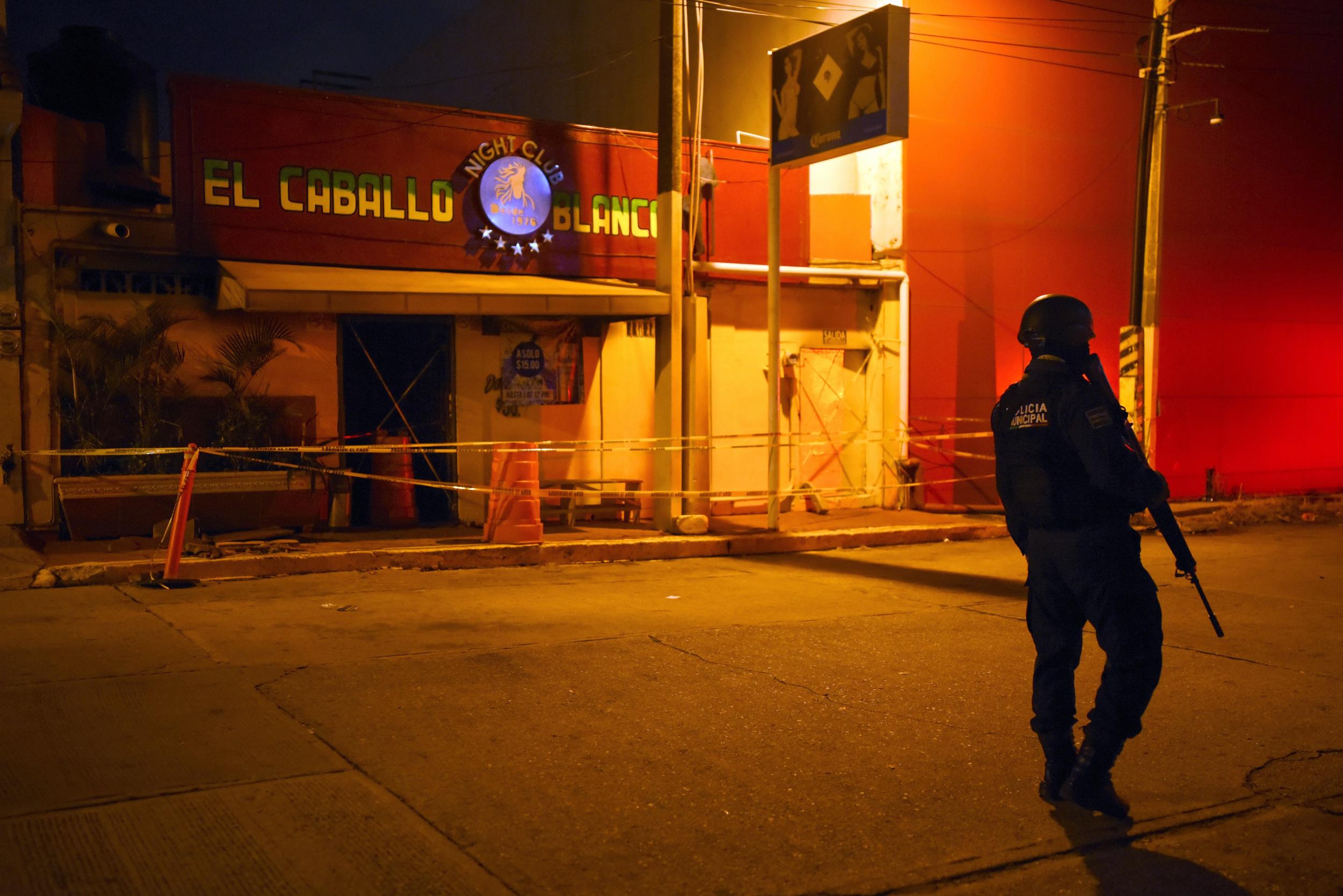 A police officer stands guard outside Caballo Blanco bar, where 25 people were killed by a fire in Coatzacoalcos, Veracruz State, earlier this year which is believed have been a fight between rival drug cartels. More killings take place in Mexico today than at any time in the last two decades