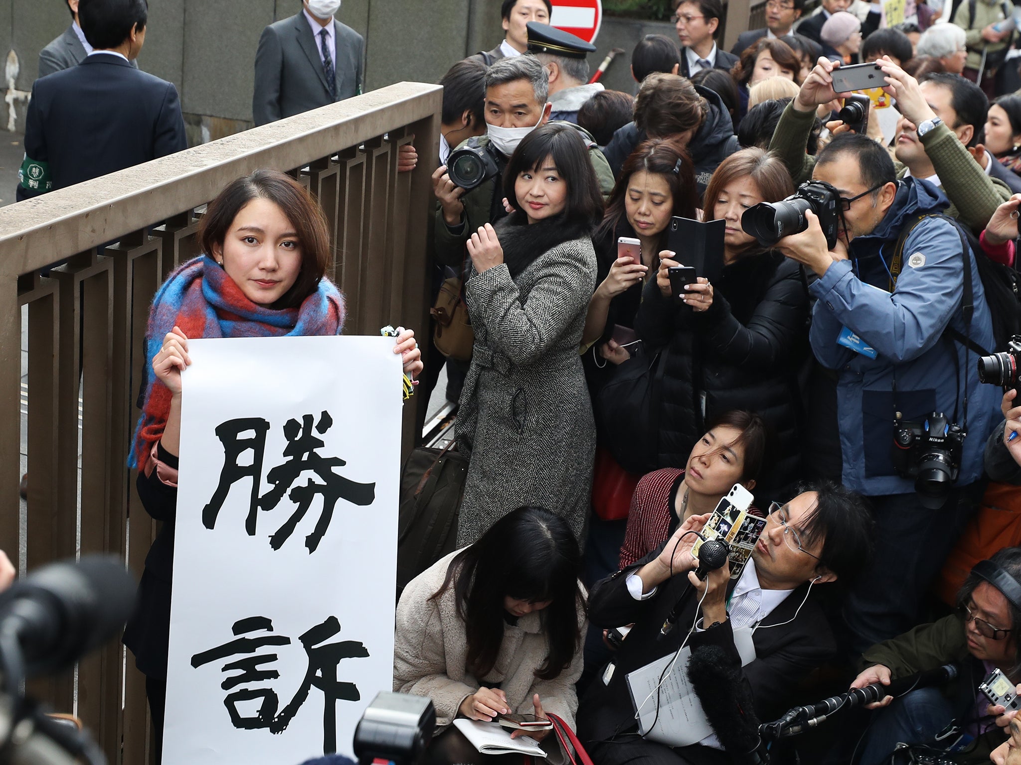 Ito holds up signs showing victory in front of the Tokyo District Court (Getty)