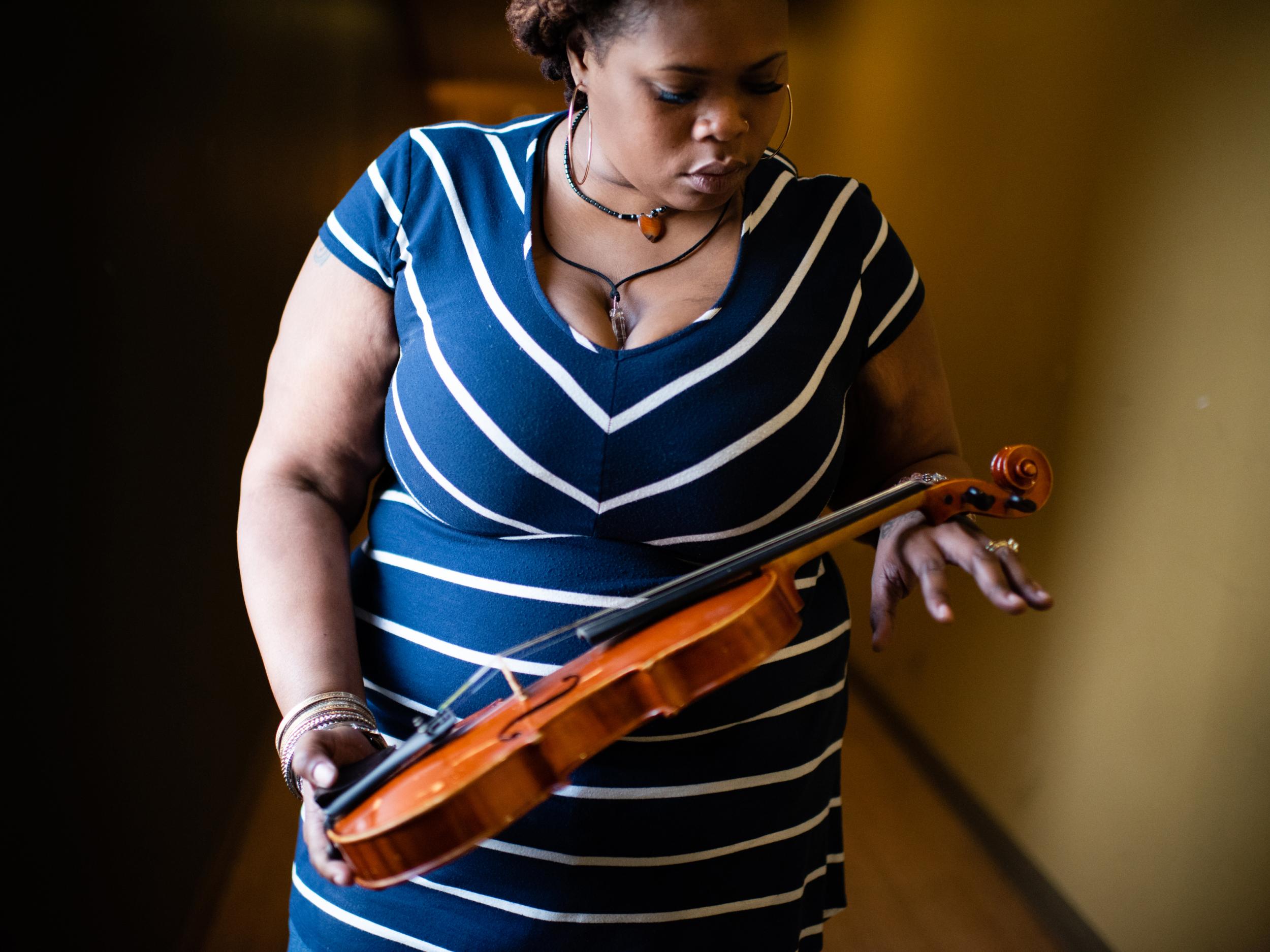 Devore Taylor holds the violin her daughter used to play