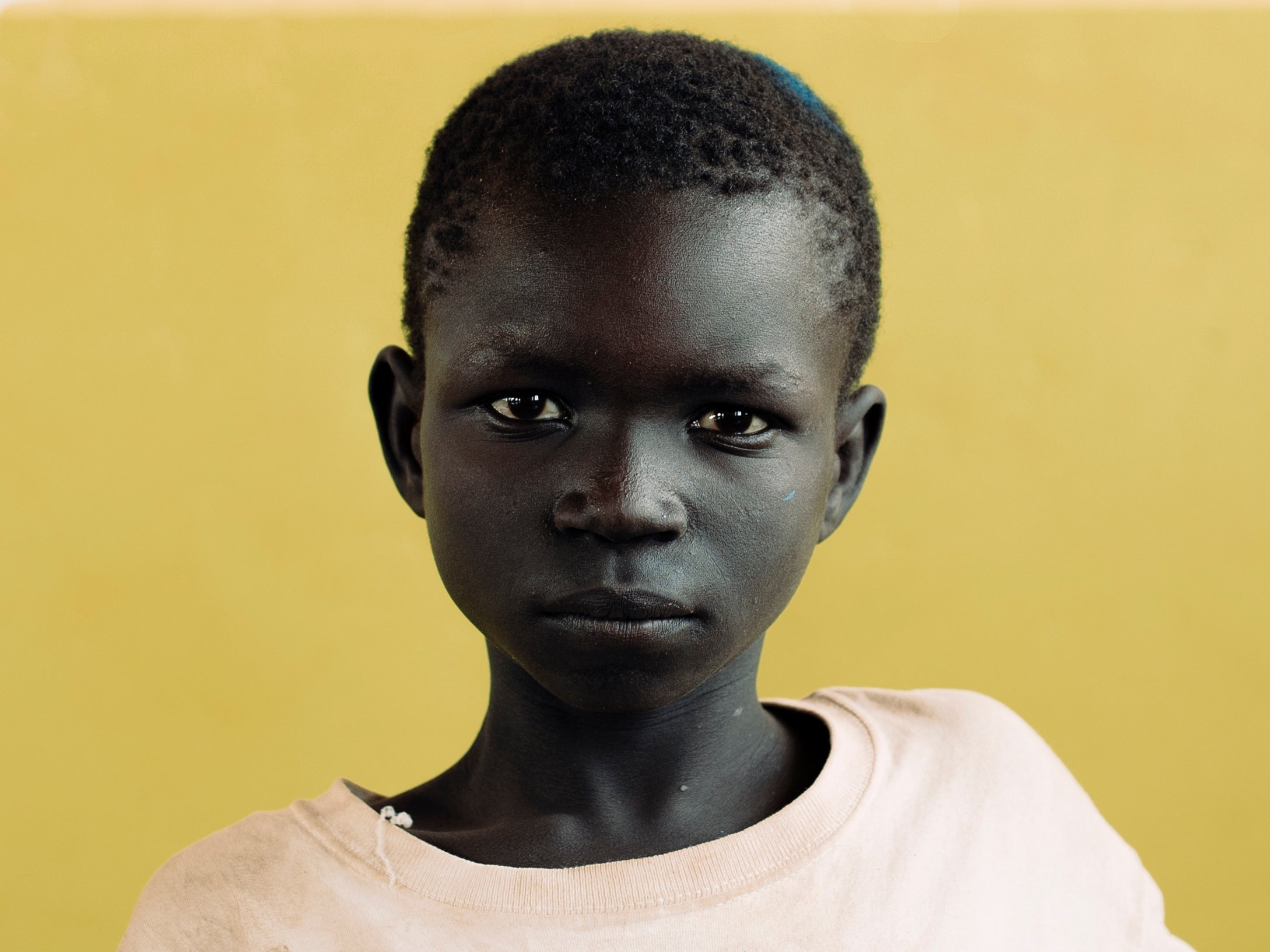 David, 13, arrived in Uganda in July 2016 fleeing the civil war that broke out in South Sudan. He arrived with his mother and father and his eight brothers and sisters after two days of walking. He recalls seeing many dead bodies lining the sides of the tracks that led to Uganda’s northern border. The family were fearful of abduction by rebel groups or becoming caught in crossfire between the government and militia groups. David enjoyed school immensely in South Sudan but said his school had closed due to conflict. He attends Alaba School at Bidi Bidi Refugee Settlement. David dreams of a better life for his family.