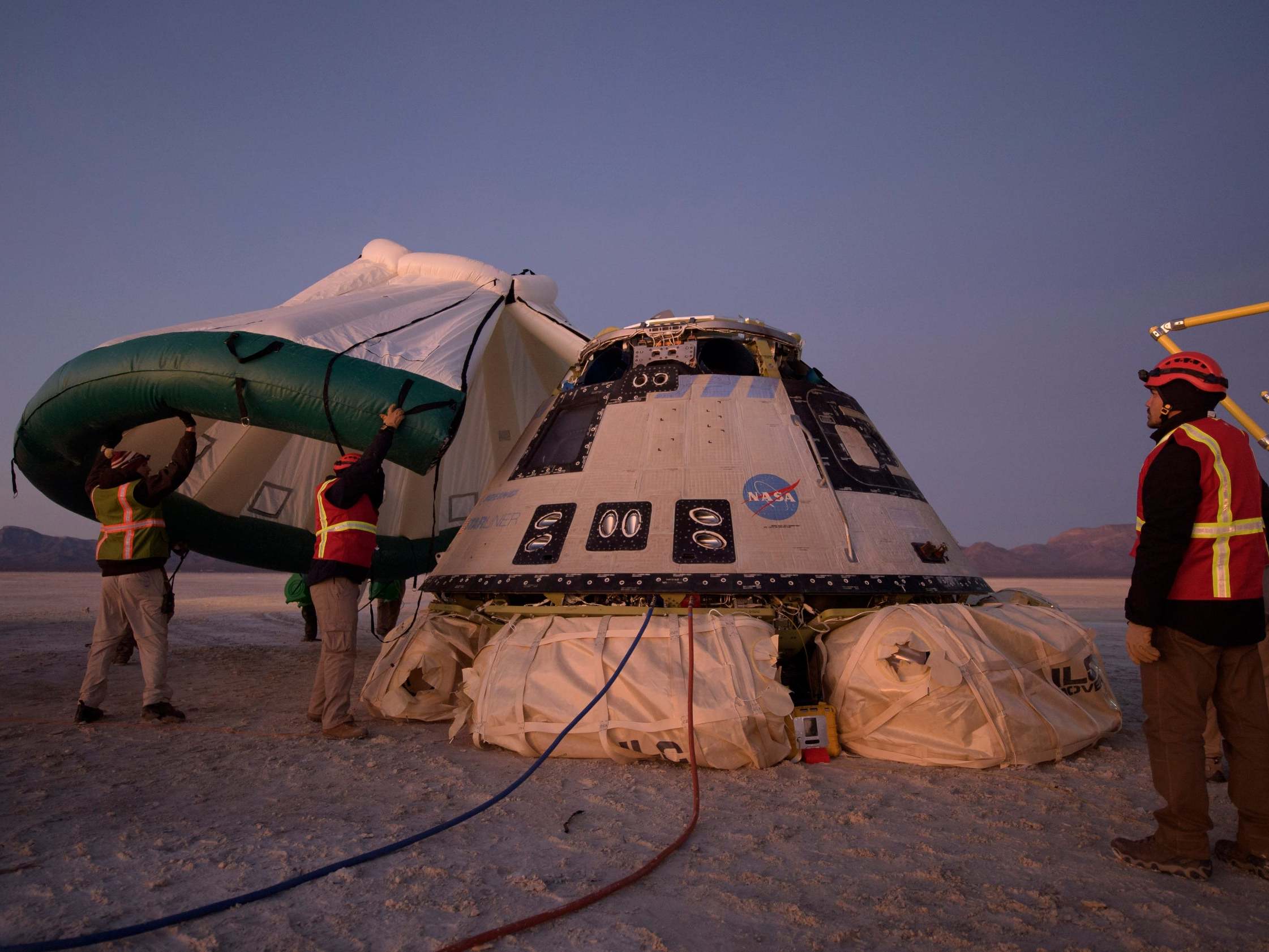 Boeing, NASA, and US Army personnel work around the Boeing Starliner spacecraft shortly after it landed in White Sands, New Mexico, 22 December, 2019.