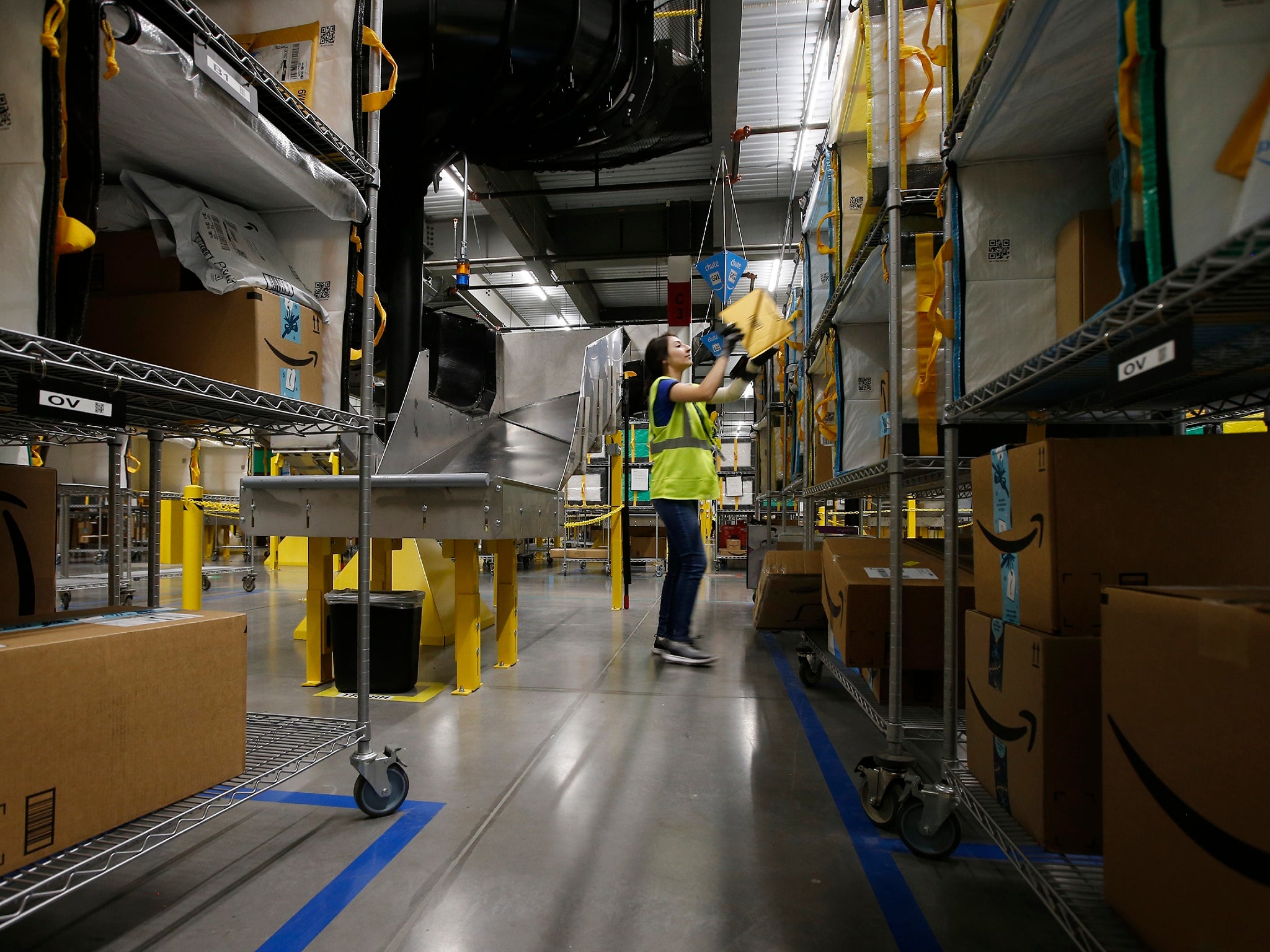 A worker stows packages into special containers after robots deliver them separated by postcode